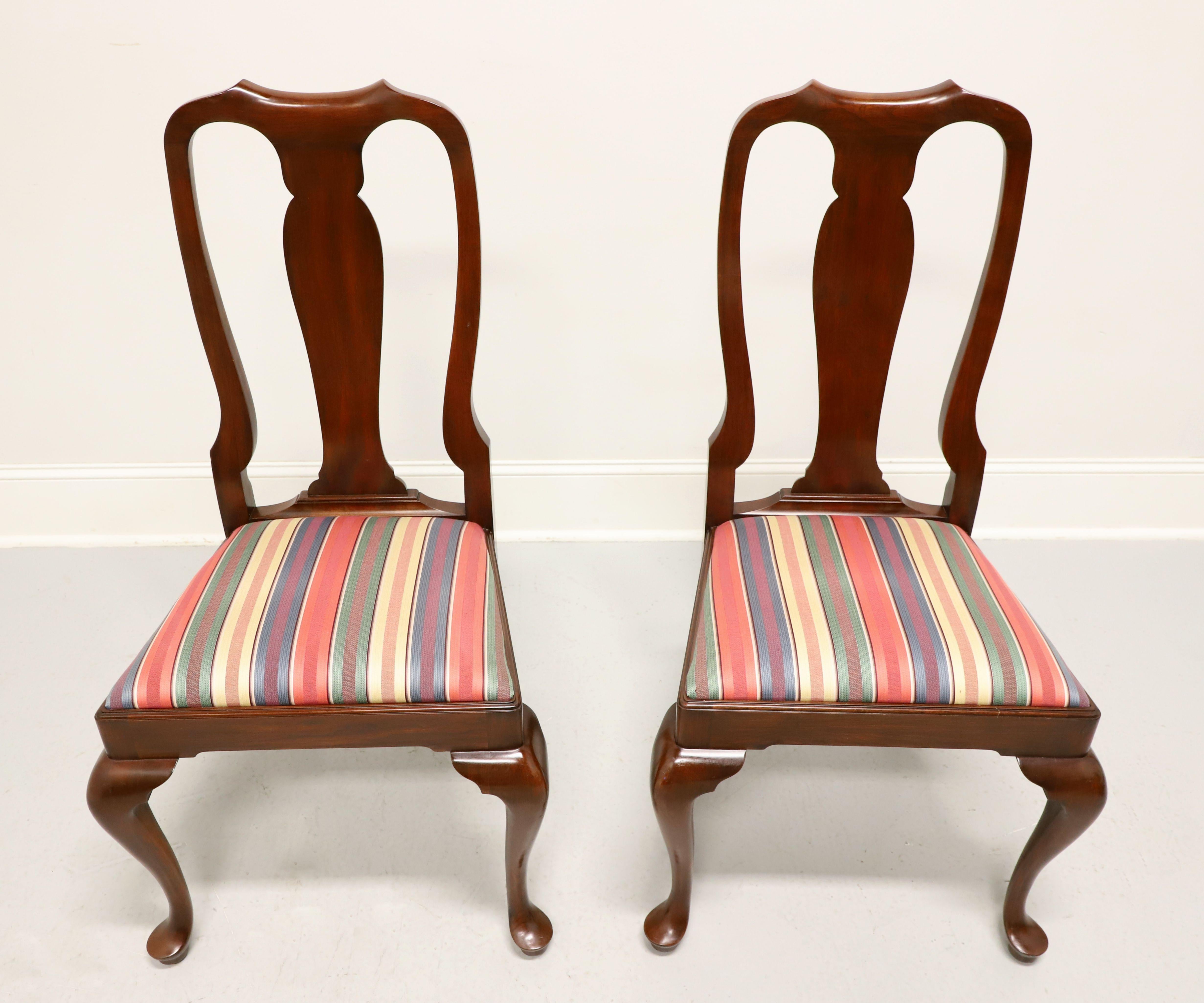 A pair of Queen Anne style dining side chairs by Henkel Harris, of Winchester, Virginia, USA. Solid wild black cherry wood, carved center backrest, upholstered seat in a multi-color stripe patterned fabric, solid apron, cabriole legs and pad feet.
