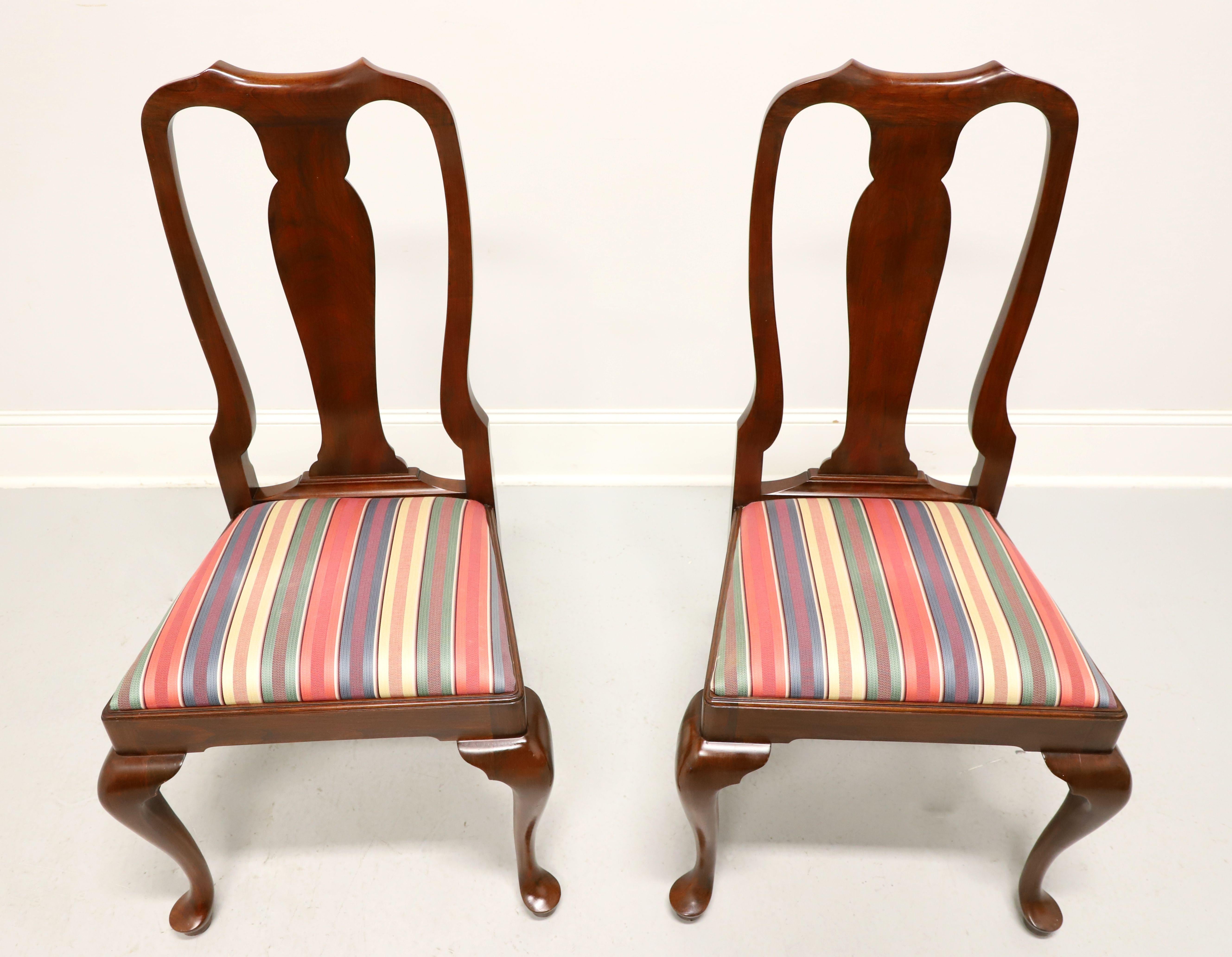 A pair of Queen Anne style dining side chairs by Henkel Harris, of Winchester, Virginia, USA. Solid wild black cherry wood, carved center backrest, upholstered seat in a multi-color stripe patterned fabric, solid apron, cabriole legs and pad feet.