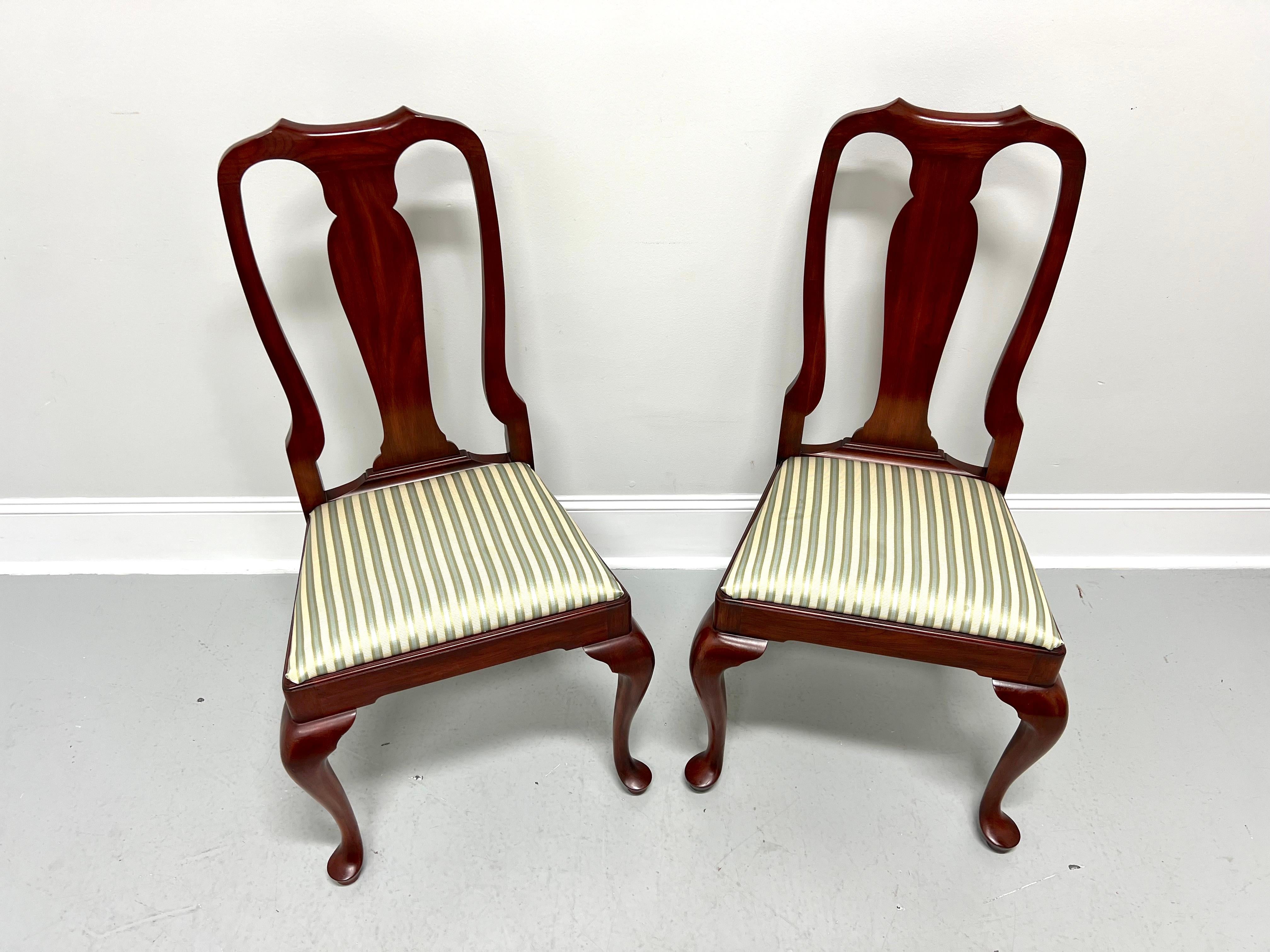 A pair of Queen Anne style dining side chairs by Henkel Harris, of Winchester, Virginia, USA. Solid wild black cherry wood, carved center backrest, upholstered seat in a multi-color stripe patterned fabric, solid apron, cabriole legs, and pad feet.