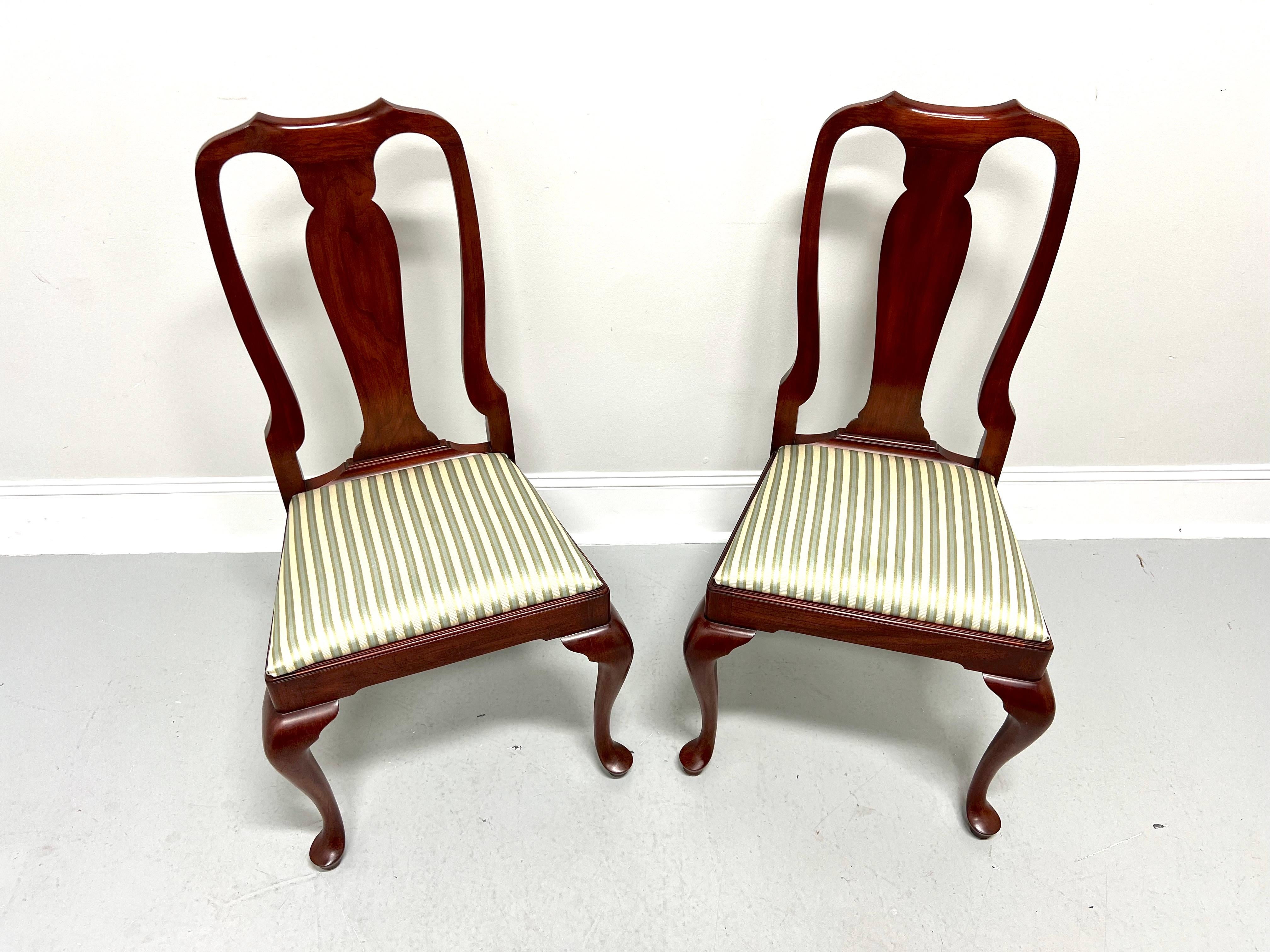 A pair of Queen Anne style dining side chairs by Henkel Harris, of Winchester, Virginia, USA. Solid wild black cherry wood, carved center backrest, upholstered seat in a multi-color stripe patterned fabric, solid apron, cabriole legs, and pad feet.