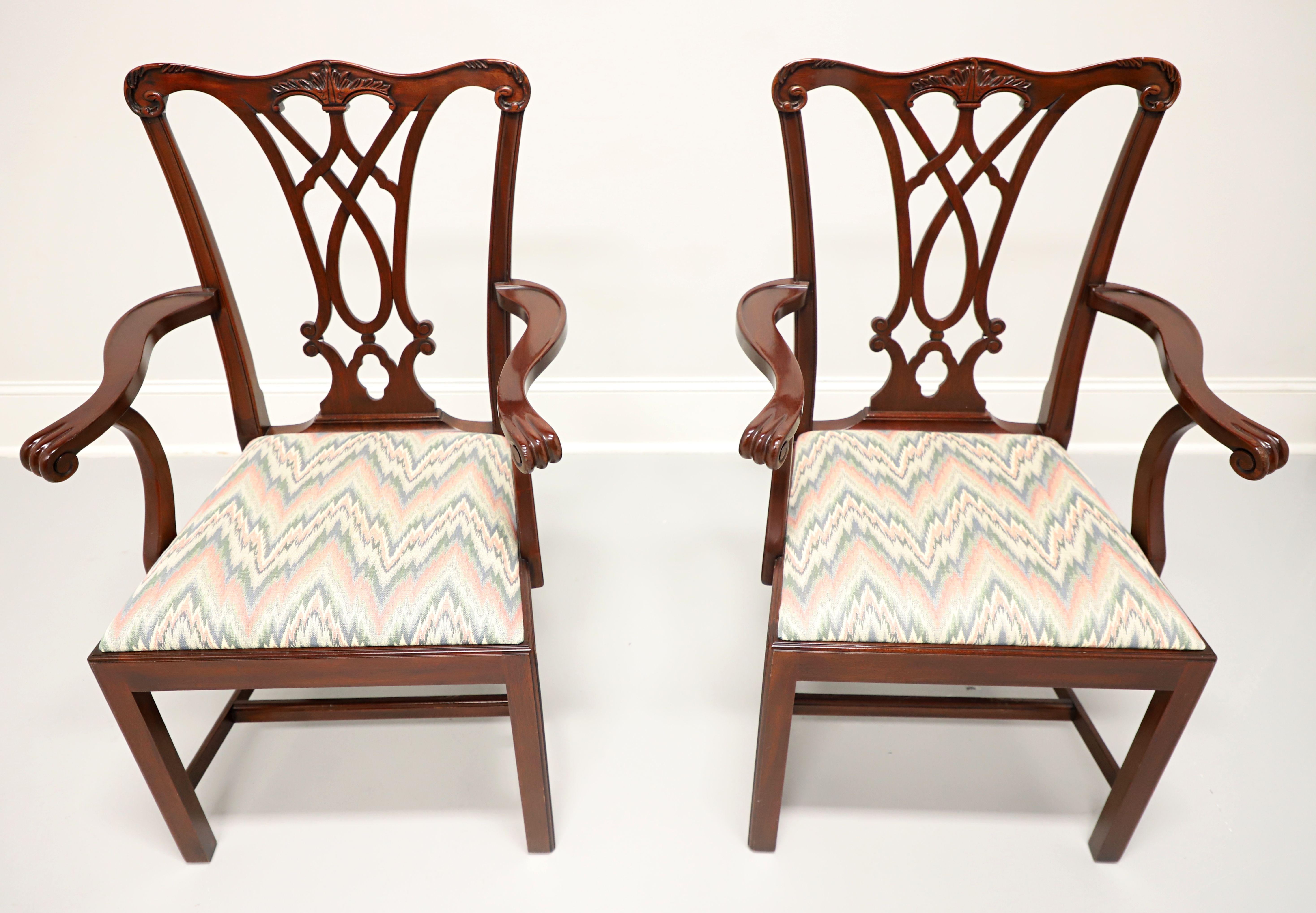 A pair of Chippendale style dining armchairs by Henkel Harris, of Winchester, Virginia, USA. Solid mahogany, carved crest rail & backrest, scroll arms, multi-color flame stitch pattern fabric upholstered seat, straight legs, and stretchers. Made