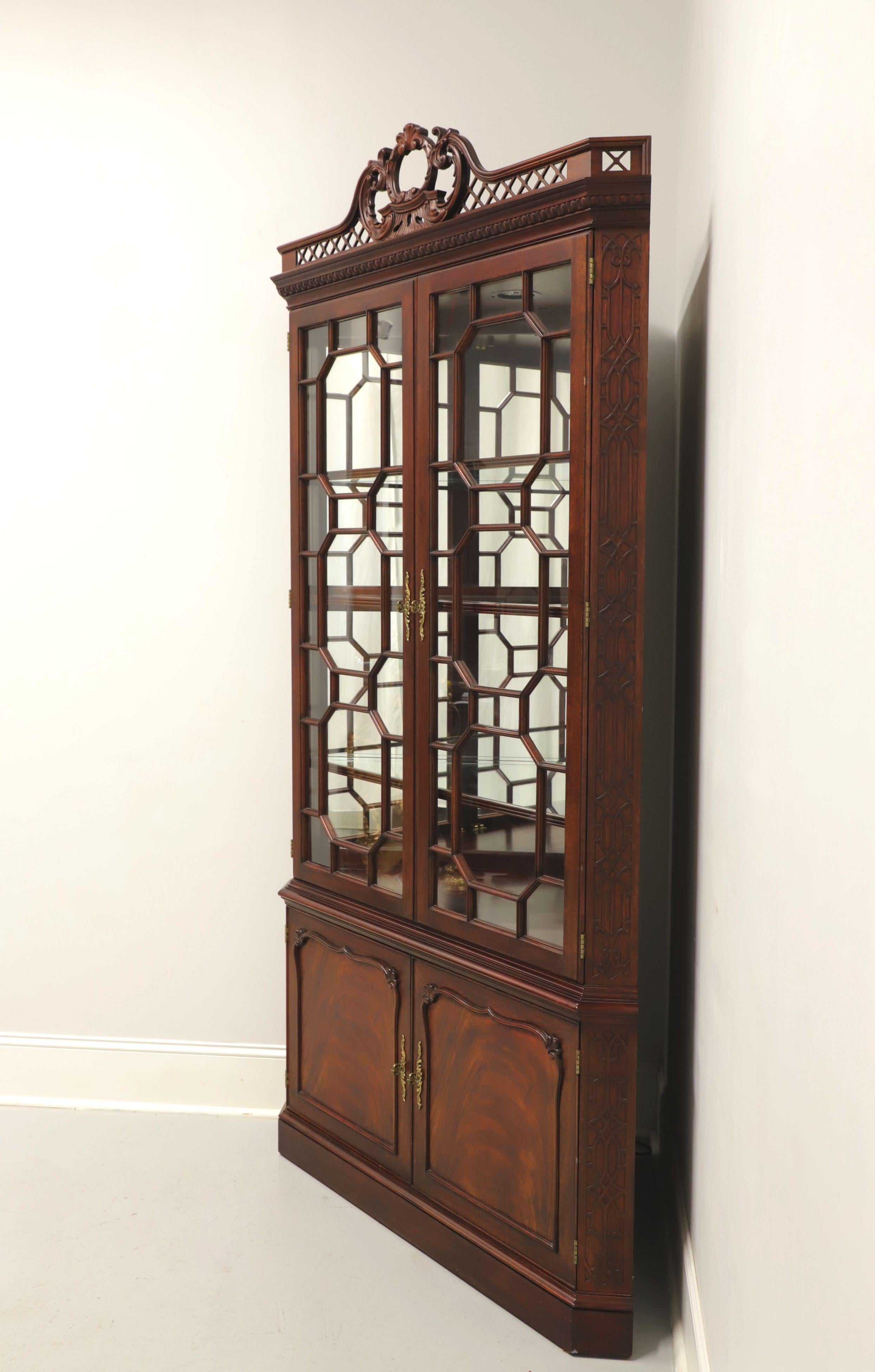 A rare find, a Chippendale style corner display cabinet by Henkel Harris, of Winchester, Virginia, USA. Solid mahogany with inlaid flame mahogany to lower doors, gorgeous carved fretwork crowning the top, fretwork over glass doors and brass