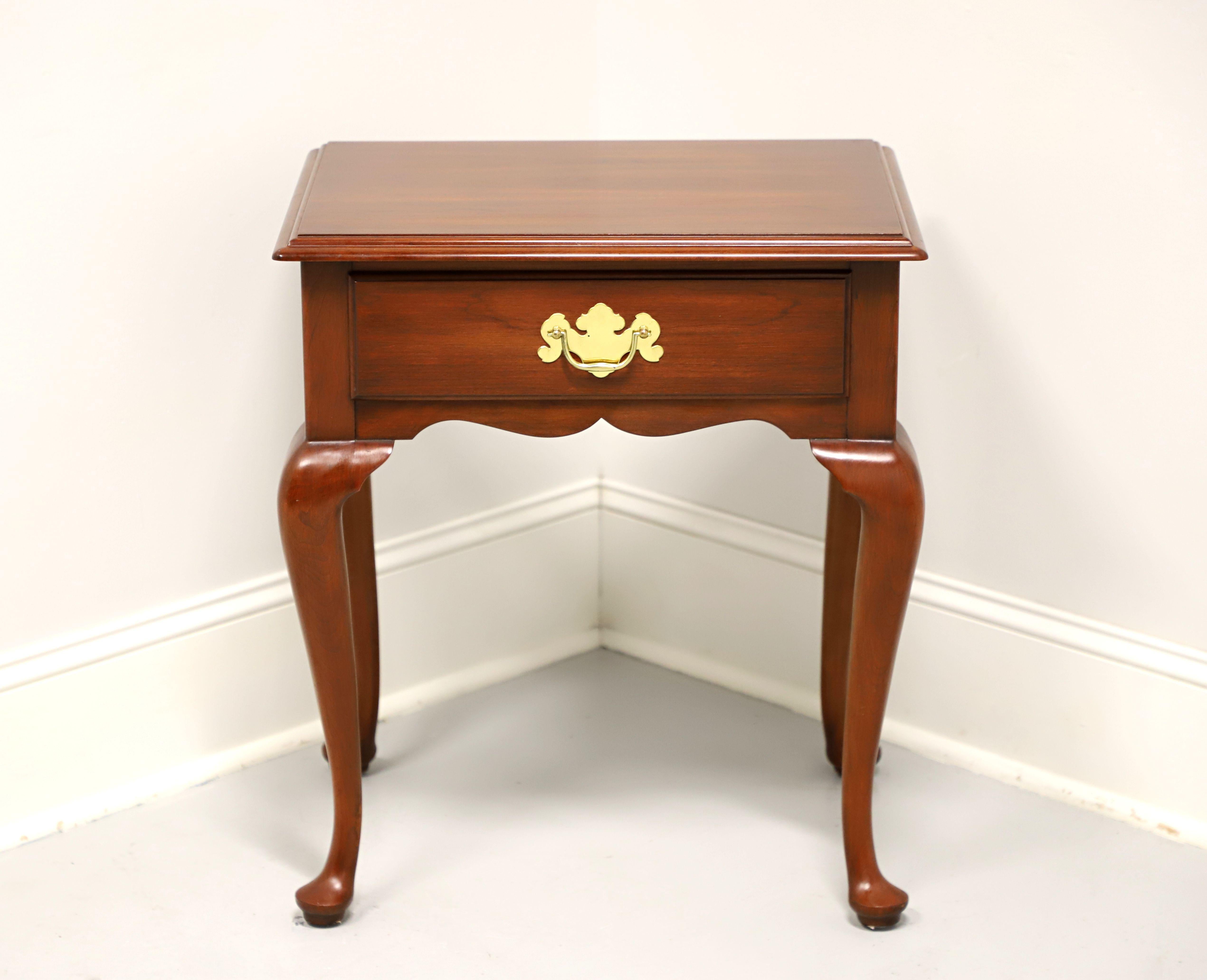 A Queen Anne style end table by Henkel Harris of Winchester, Virginia, USA. Solid wild black cherry wood with brass hardware, ogee edge to the top, carved apron, cabriole legs and pad feet. Features one drawer of dovetail construction. Made circa