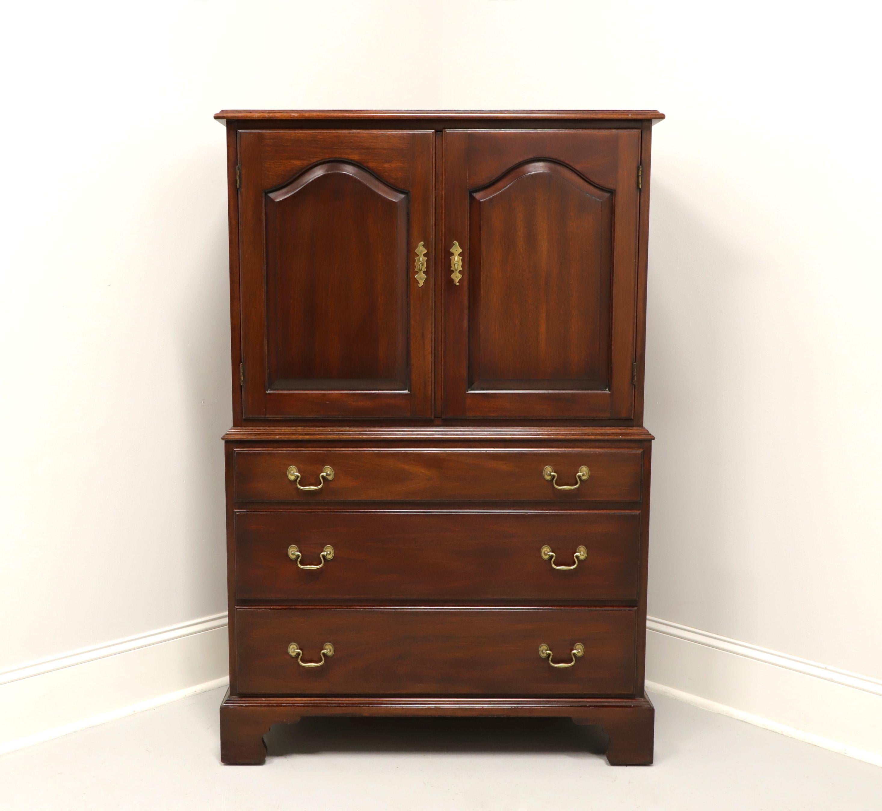 A Chippendale style gentleman's chest by Henkel Harris, of Winchester, Virginia, USA. Solid mahogany with brass hardware and bracket feet. Upper cabinet features double doors revealing six cubbies and one dovetail drawer with two fixed dividers.