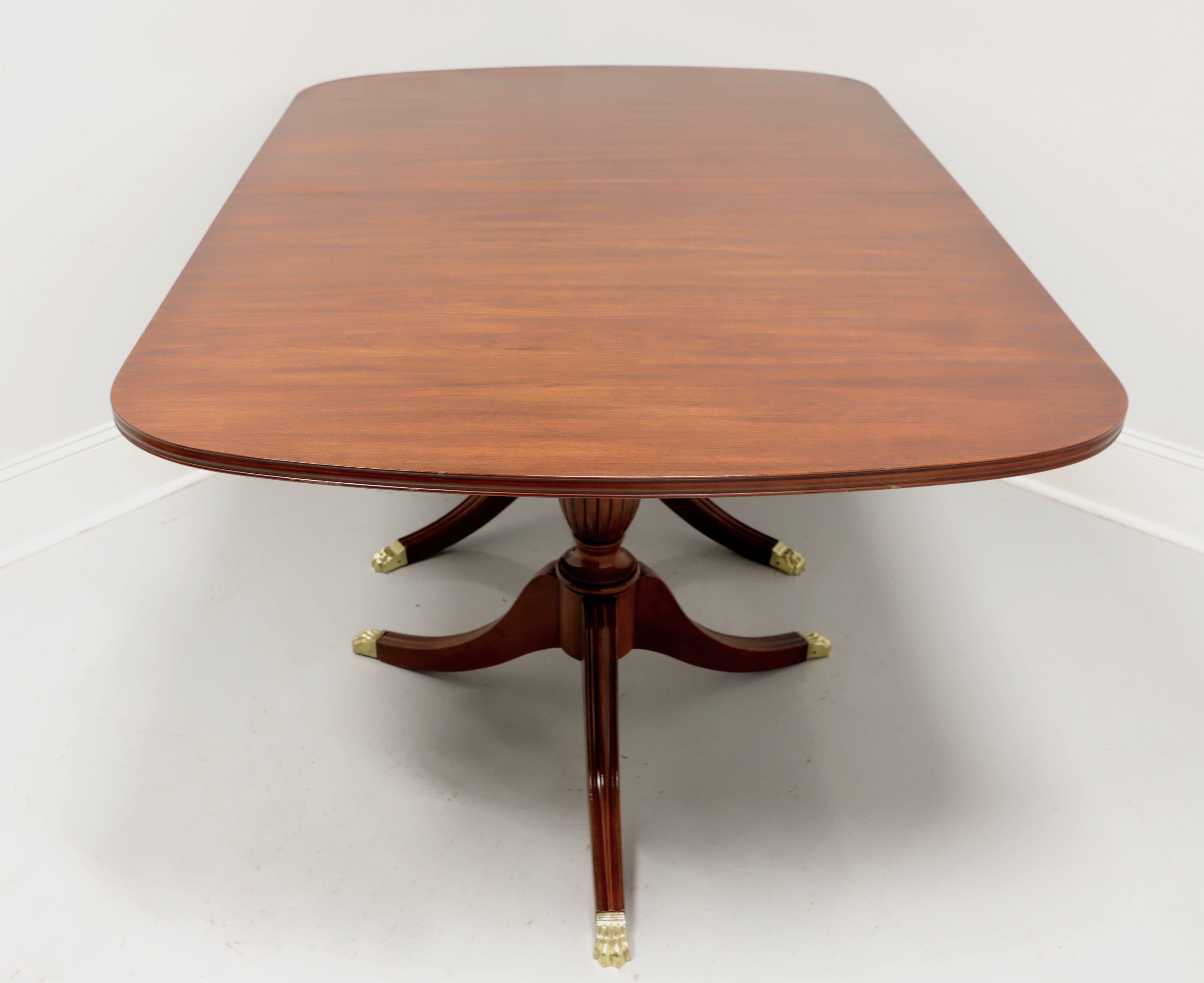 A Traditional style dining table by Henkel Harris, of Winchester, Virginia, USA. Solid Wild Black Cherry with a rectangular top that sits on two pedestals, each with three fluted legs and brass paw toe caps. Wood expansion sliders. Includes three