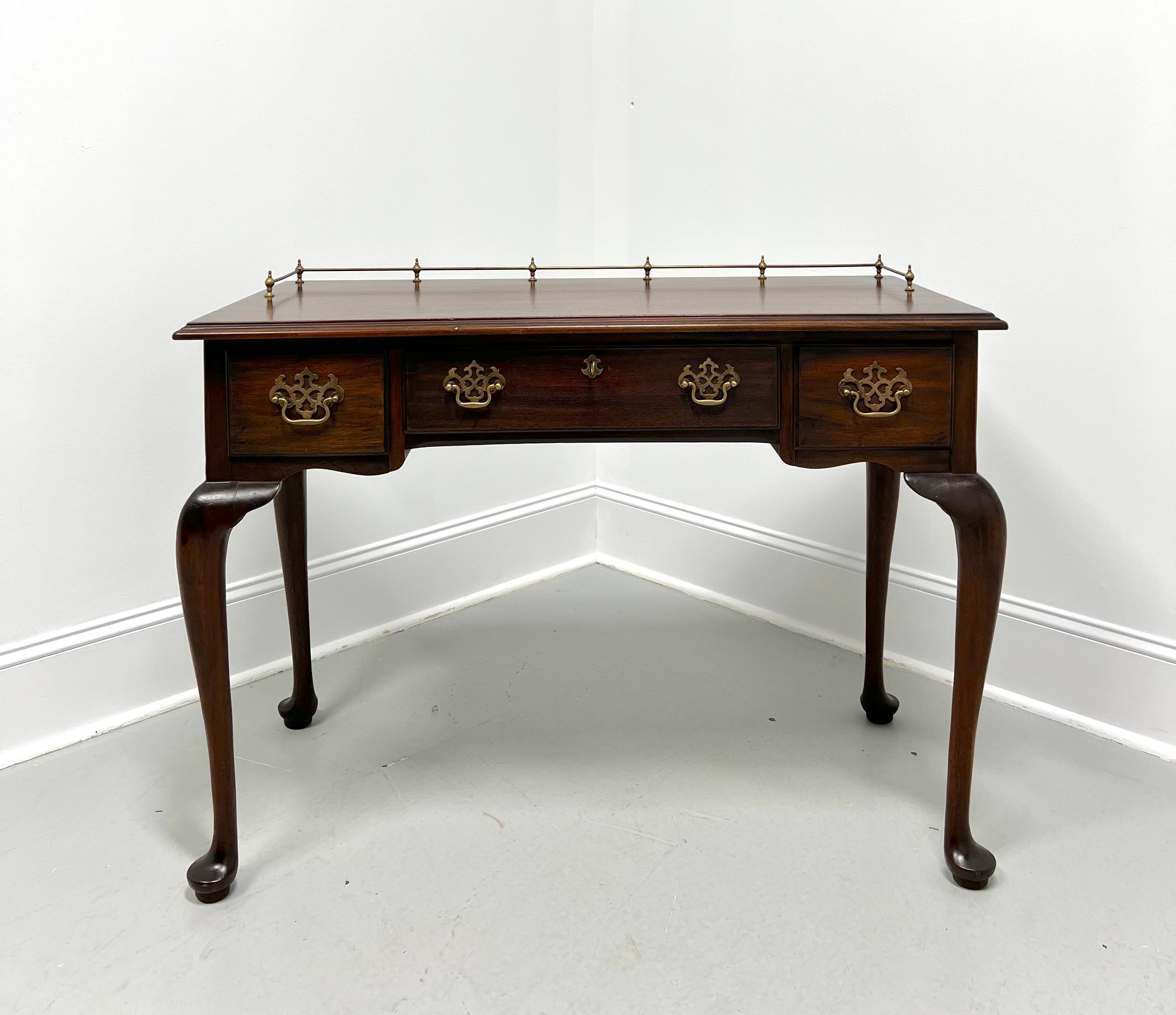 A Queen Anne style writing desk by Henkel Harris, of Winchester, Virginia, USA. Solid mahogany with a distressed finish, decorative brass hardware, an ogee edge to the top, brass rail gallery, cabriole legs, and pad feet. Features one large lockable