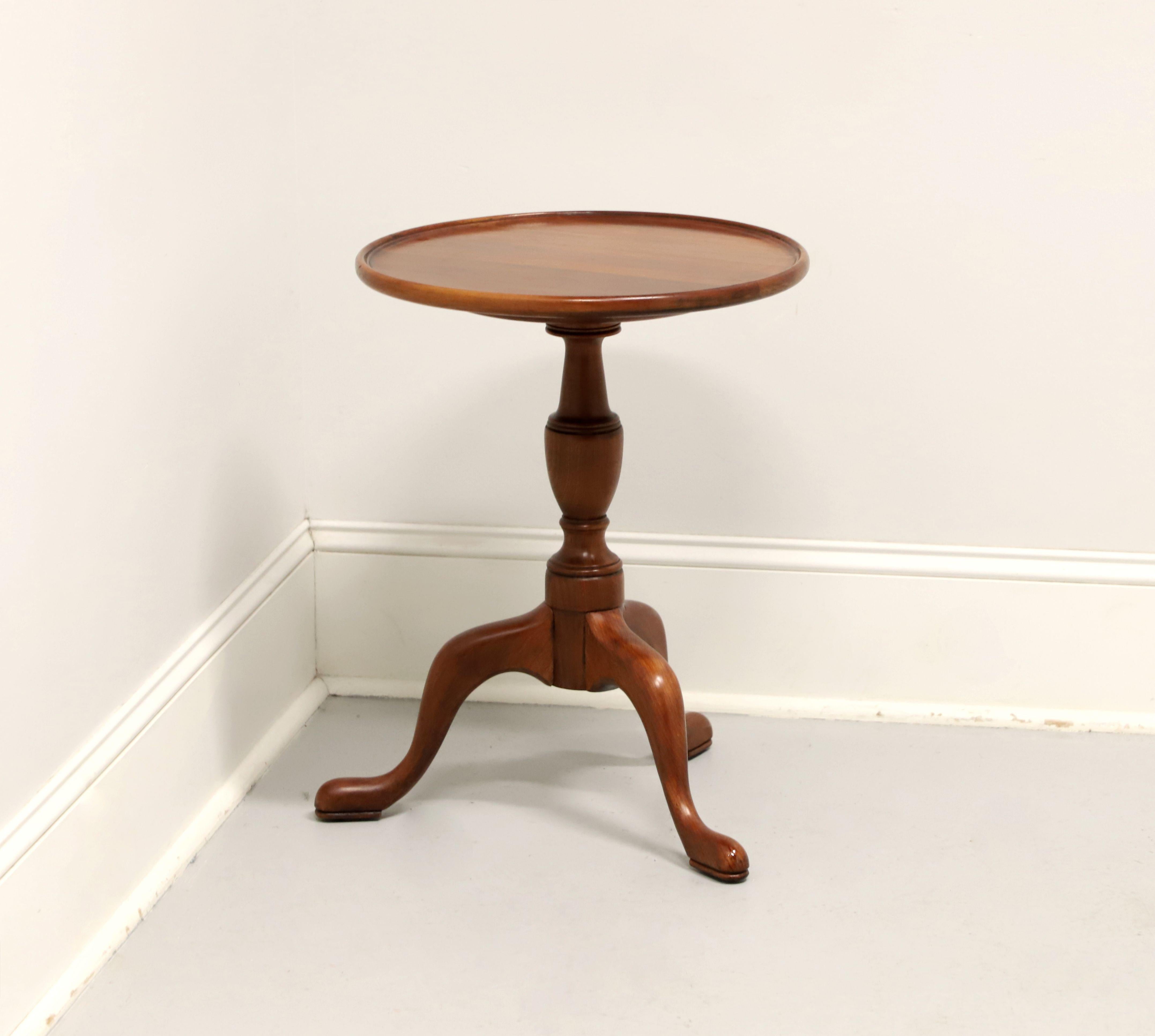 A Georgian style round brandy stand / candle stand by Henkel Harris, of Winchester, Virginia, USA. Solid wild black cherry wood with round raised lip top, turned singular pedestal base, and three legs with pad feet. Made circa 1972.

Style #: 5607,