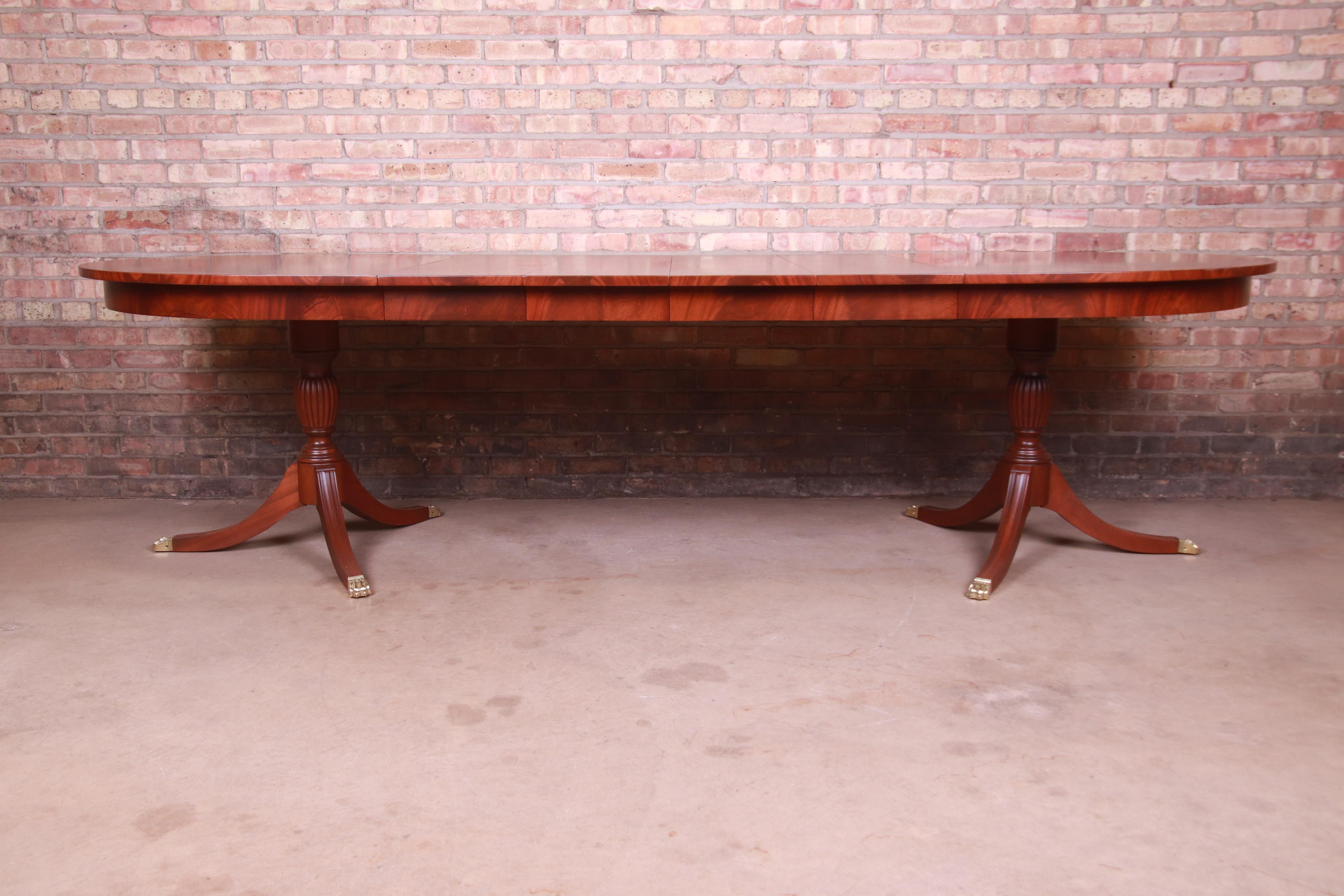 An exceptional Georgian style double pedestal extension dining table

By Henkel Harris

USA, 1970s

Book-matched mahogany, with flame mahogany banding, satinwood string inlay, carved solid mahogany pedestals, and brass-capped