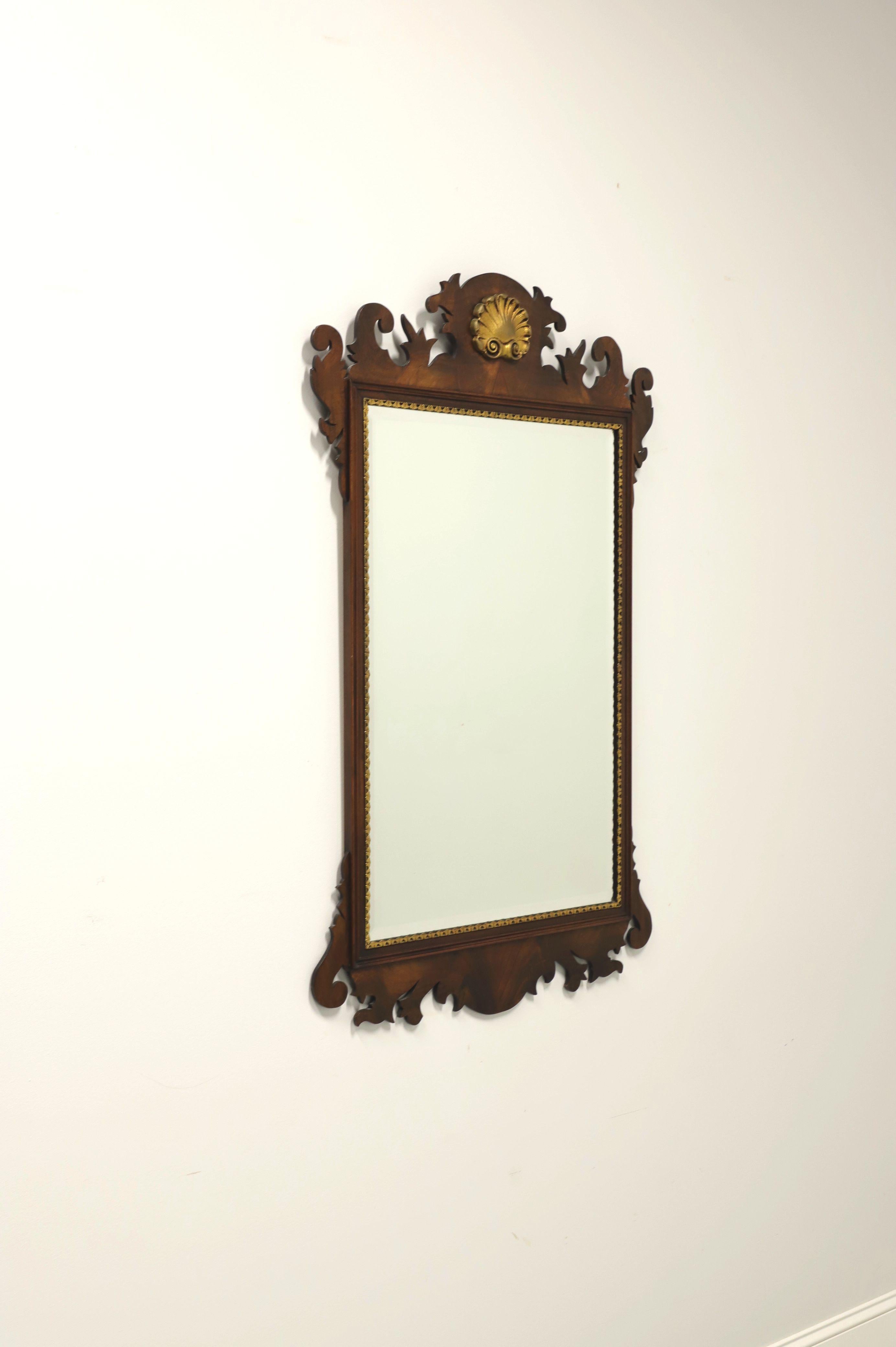 A Chippendale style wall mirror by Henkel Harris, of Winchester, Virginia, USA. Bevel edge mirrored glass, flame mahogany frame with gold trim and top center gold gilt shell shaped medallion. Made in the late 20th Century

Style #: H-6, Finish: 29
