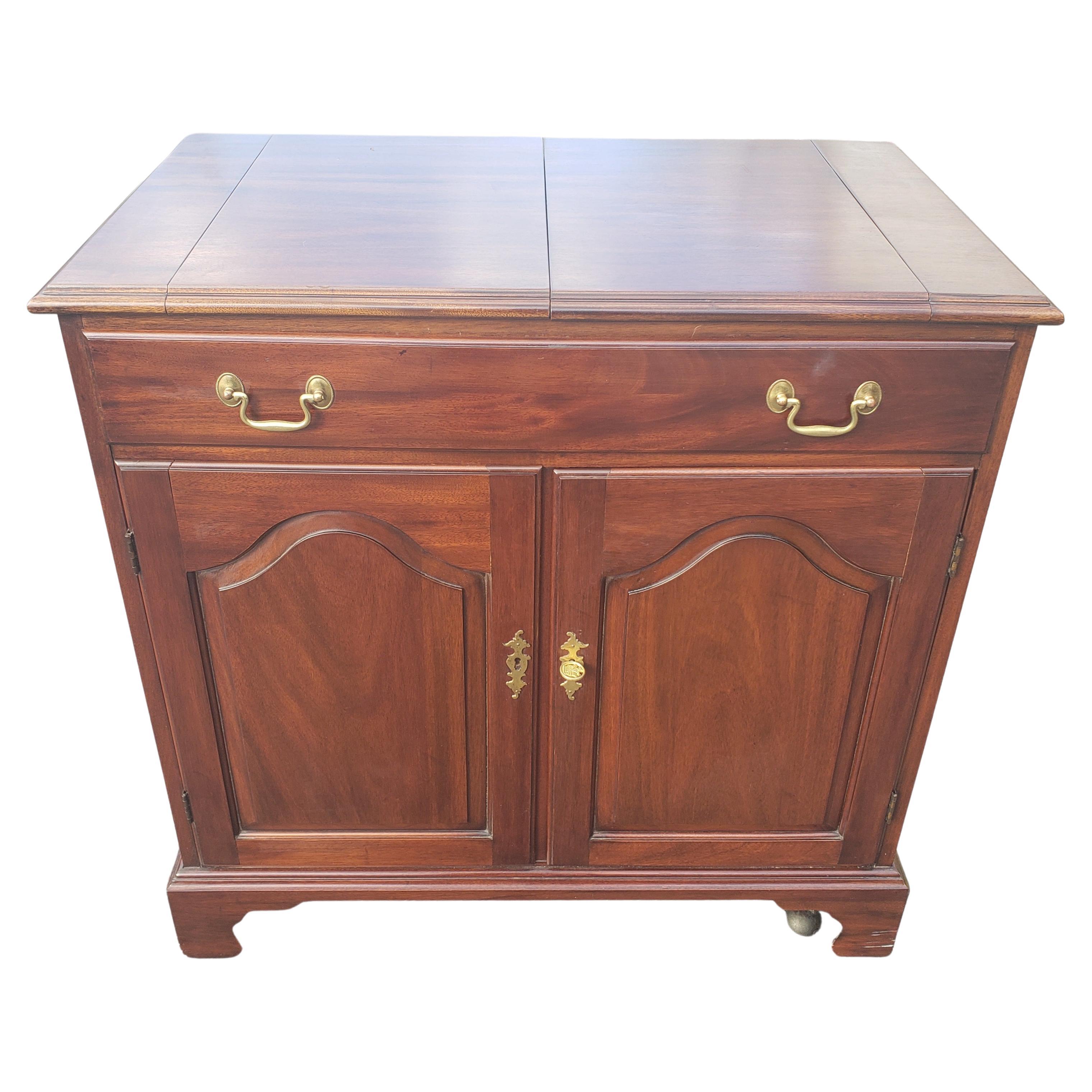 Solid Mahogany dry bar and buffet server by Henkel Harris. 
It features one large compartmented dovetailed drawer, a storage compartment with shelf and brass hardware.
On Very solid rolling casters . Very good vintage condition.
Measures 34