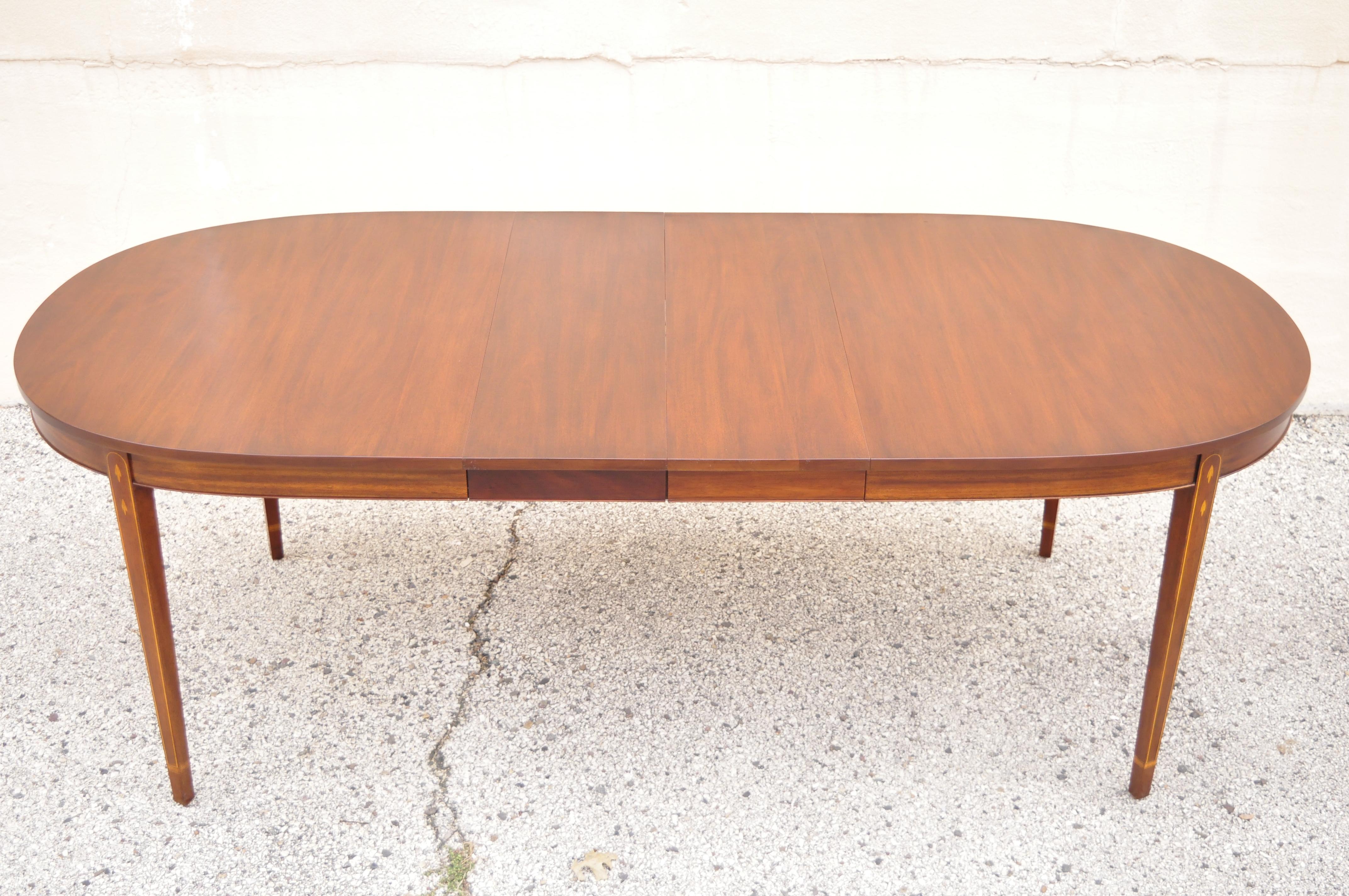 Henkel Harris oval mahogany dining room table with inlaid legs and two leaves. Item features (2) 12