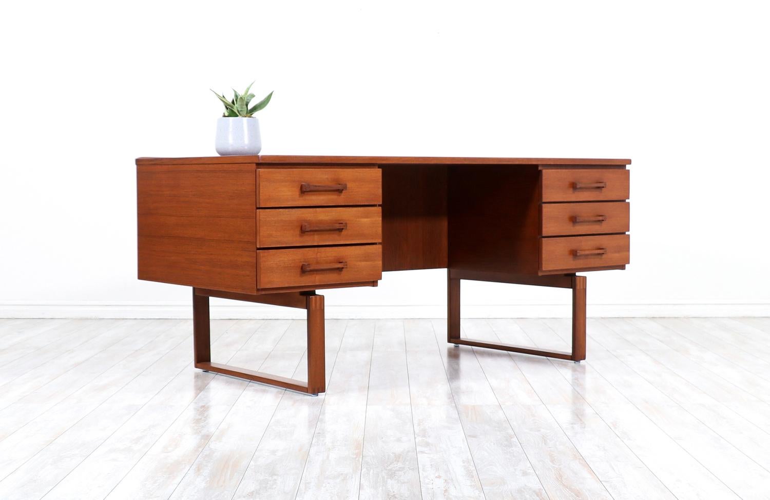 One of our most striking executive desks designed by Henning Jensen & Torbin Valeur in collaboration with the workshop of Dyrlund in Denmark during the 1960s. Our elegant Scandinavian desk features a solid teak frame with a stunning warm grain