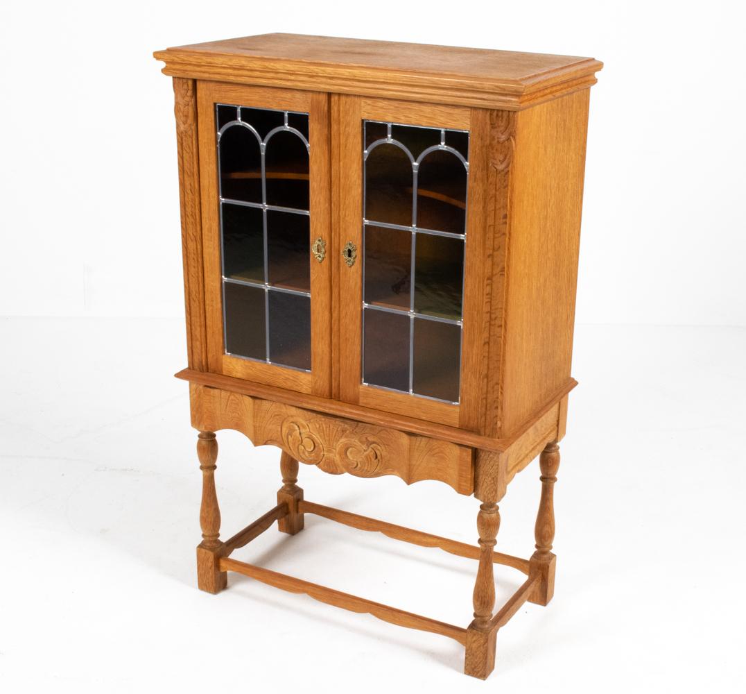 A gorgeous Danish midcentury farmhouse Provincial-style cabinet with leaded glass doors. Finely crafted of sturdy, carved oak with an unusual figured 