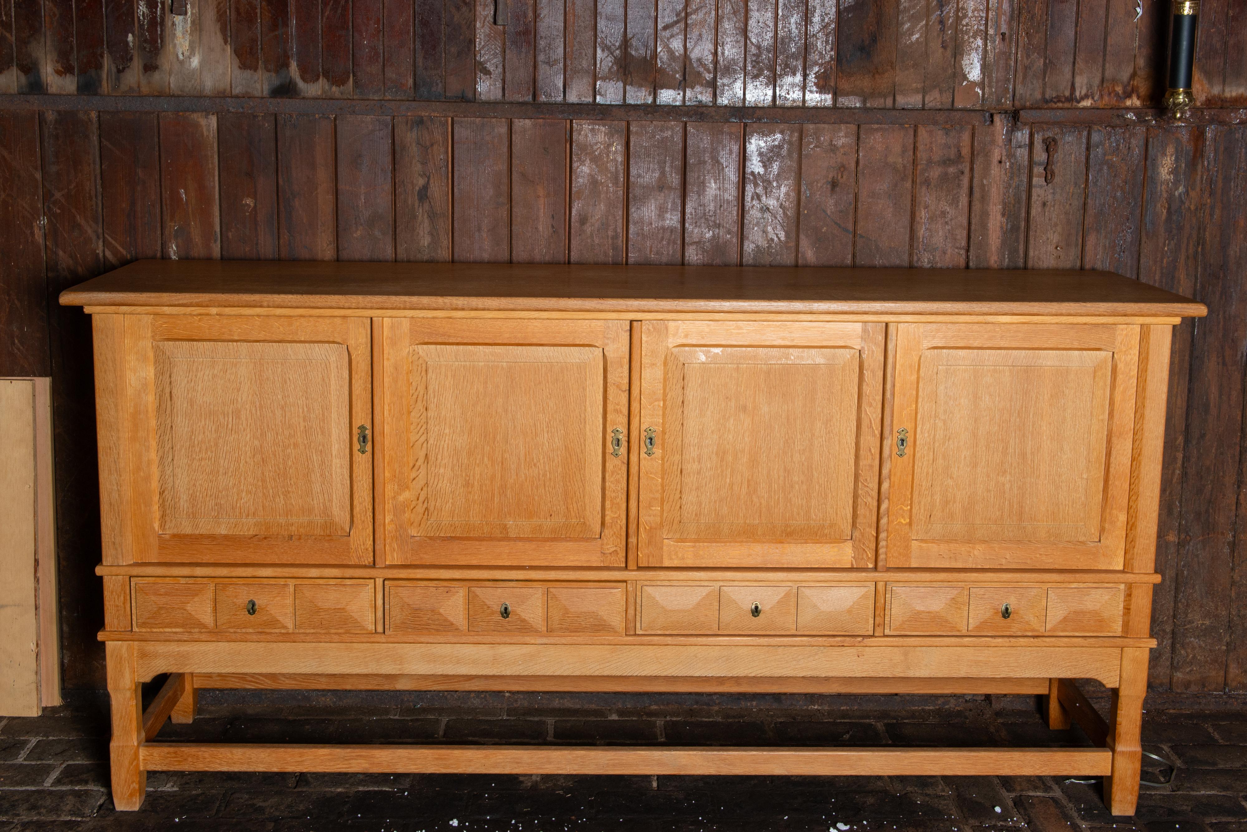 This solid white oak quarter sawn Danish sideboard is attributed to Henning 
Kjaernulf. This sideboard features four beveled doors. The center two doors
open to a single large space with two shelves. The right single door opens to 
a two shelf