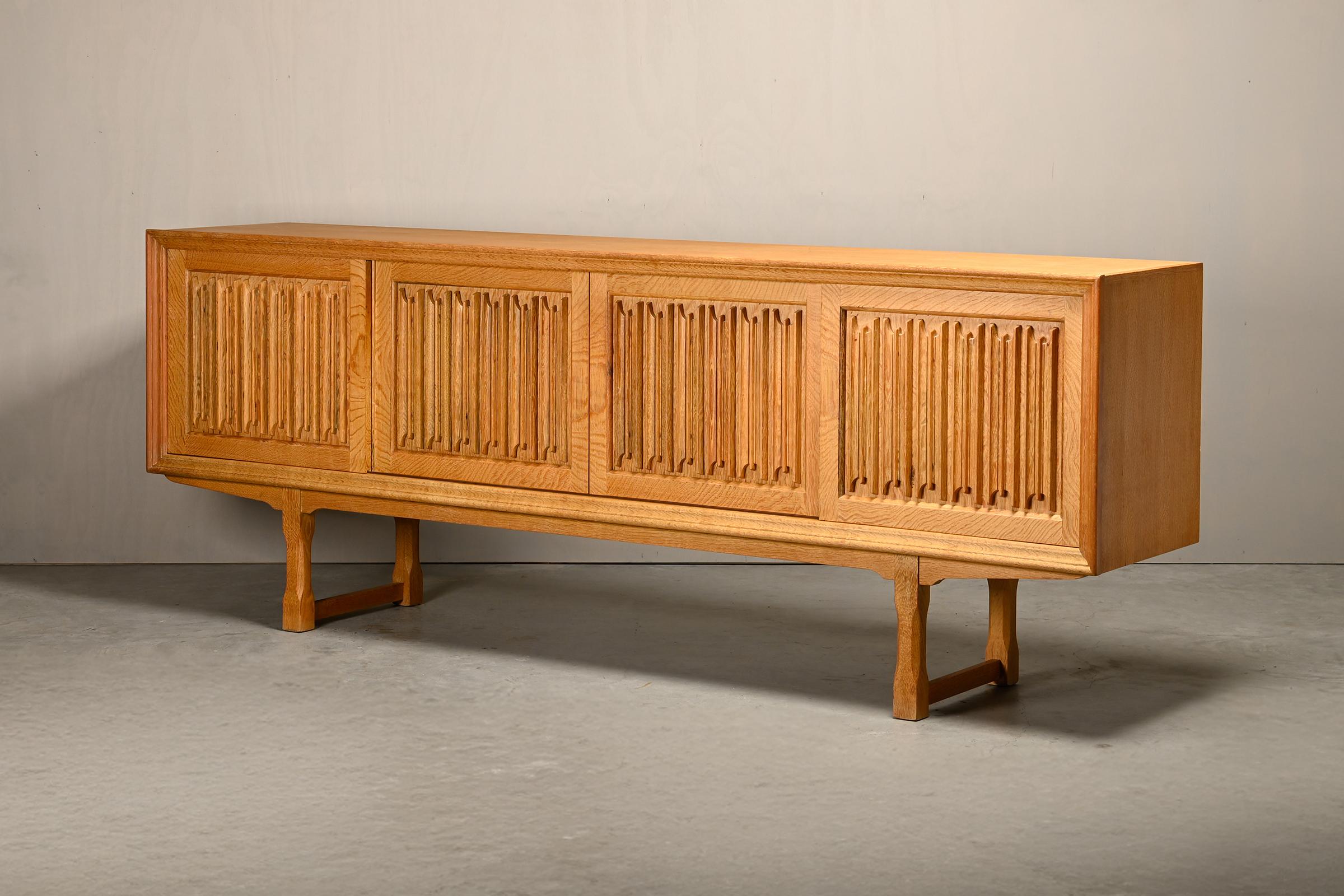 Sculptural rectangular Brutalist sideboard attributed to Henning Kjærnulf for Nyrup Møbelfabrik / EG Kvalitetsmøbler, Denmark, 1960s. Behind the four sliding doors with carved ornaments is ample storage space with two shelves and five drawers. Very