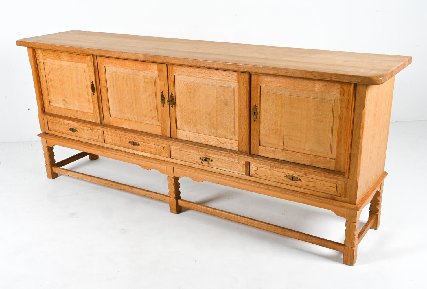 The organic beauty of quarter-sawn white oak takes center stage in this stately sideboard cabinet by the legendary architect Henning Kjærnulf. In this piece, Kjærnulf shows some restraint - opting for timeless paneled molding on the doors and a