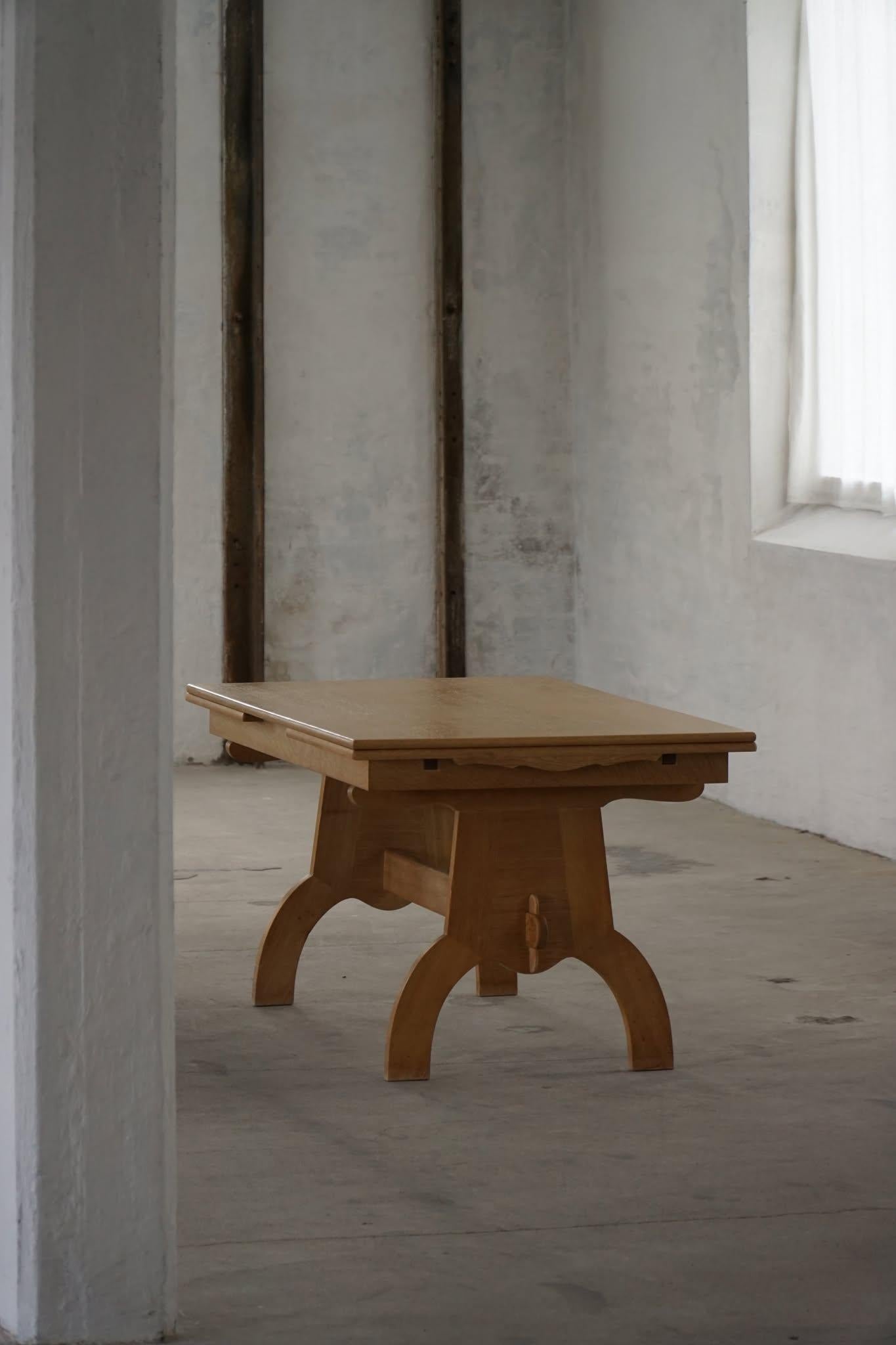 Une table de salle à manger en chêne magnifiquement travaillée, conçue par Henning Kjærnulf, qui met en valeur l'élégance et la fonctionnalité du design scandinave du milieu du siècle. La table présente des pieds en A légèrement arrondis et des