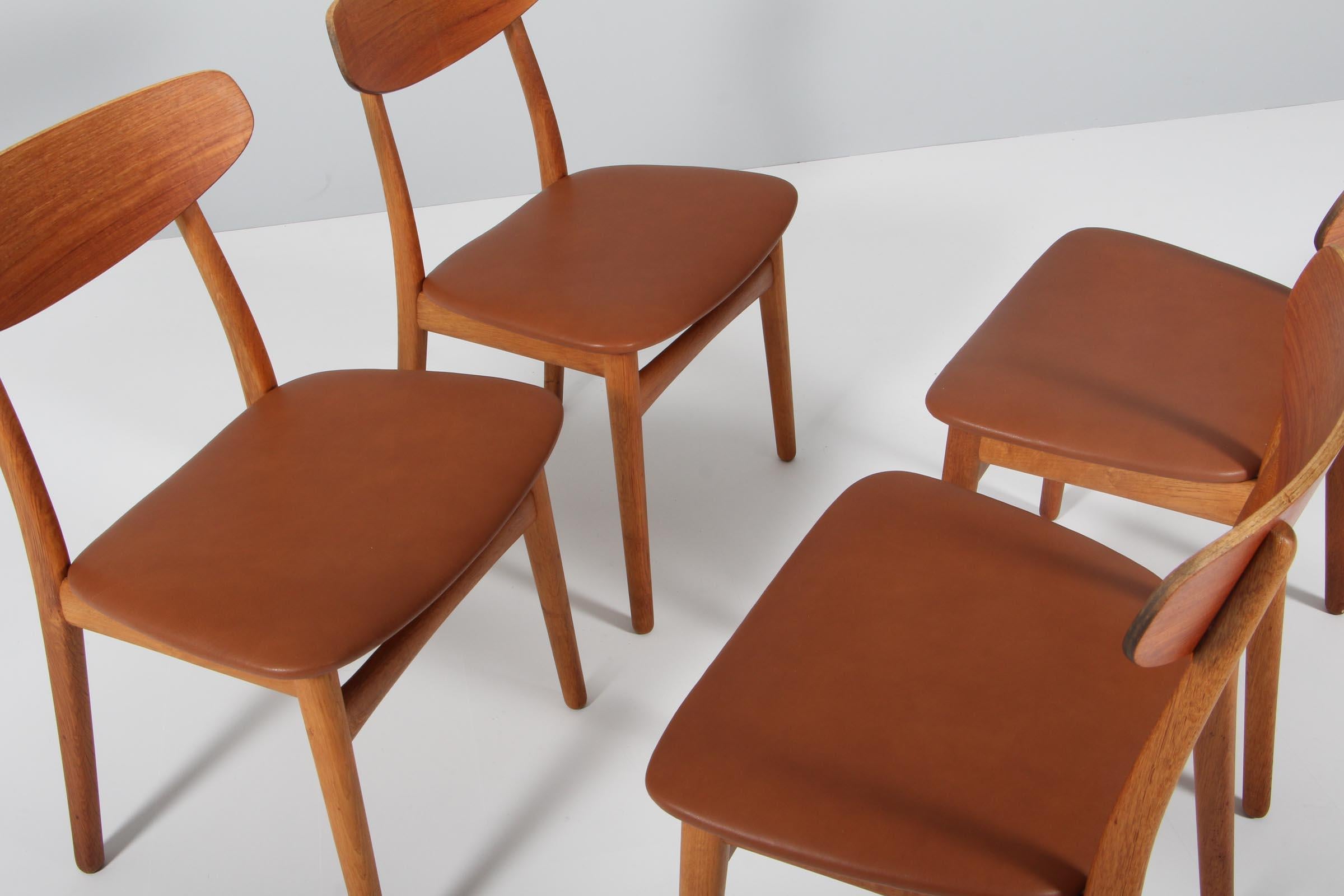 Henning Kjærnulf four dining chairs, upholstered with aniline leather.

Made of oak and teak.

Made by Bruno Hansen.