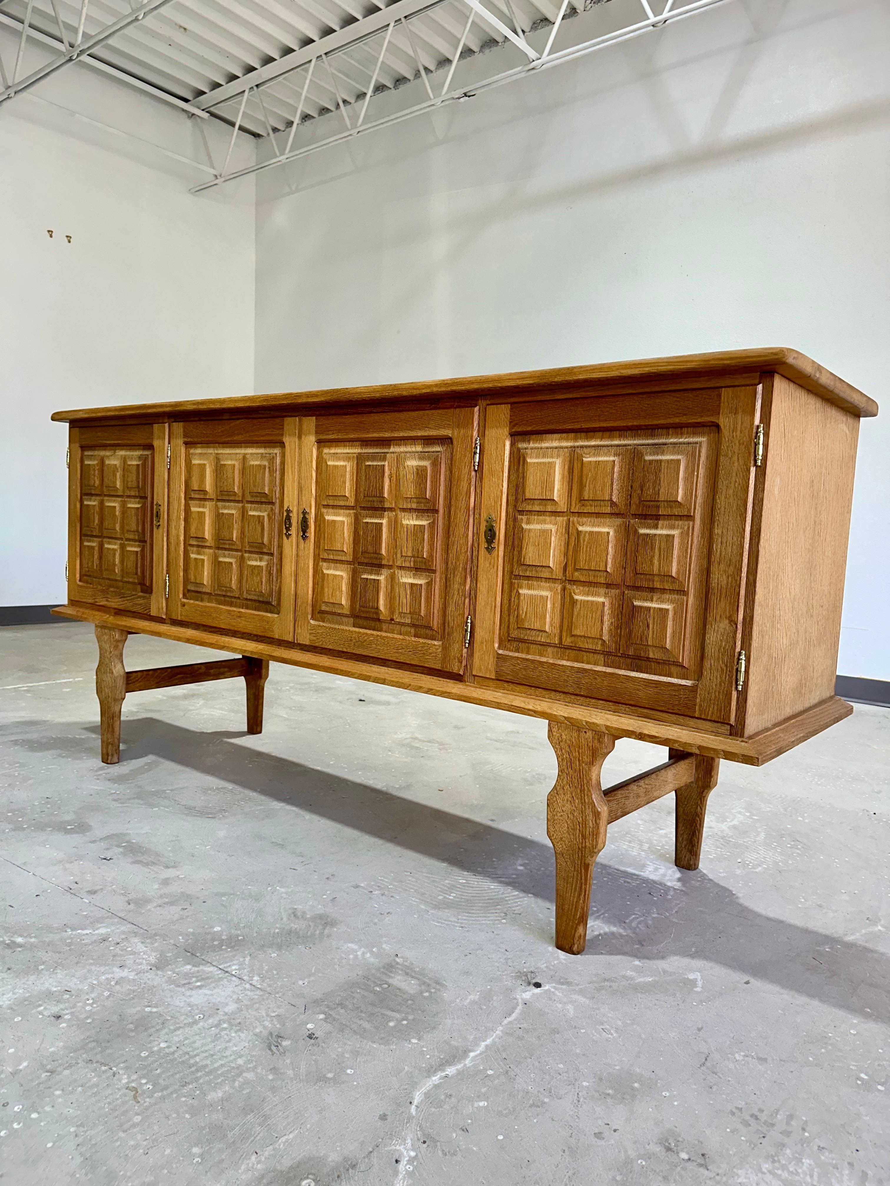 Danish solid oak brutalist credenza c.1960’s’s attributed to Henning Kjaernulf. Four locking door carved front credenza, comes with 3 keys. Square relief pattern on doors, and tall sculptural legs. An unusual statement piece that would blend well