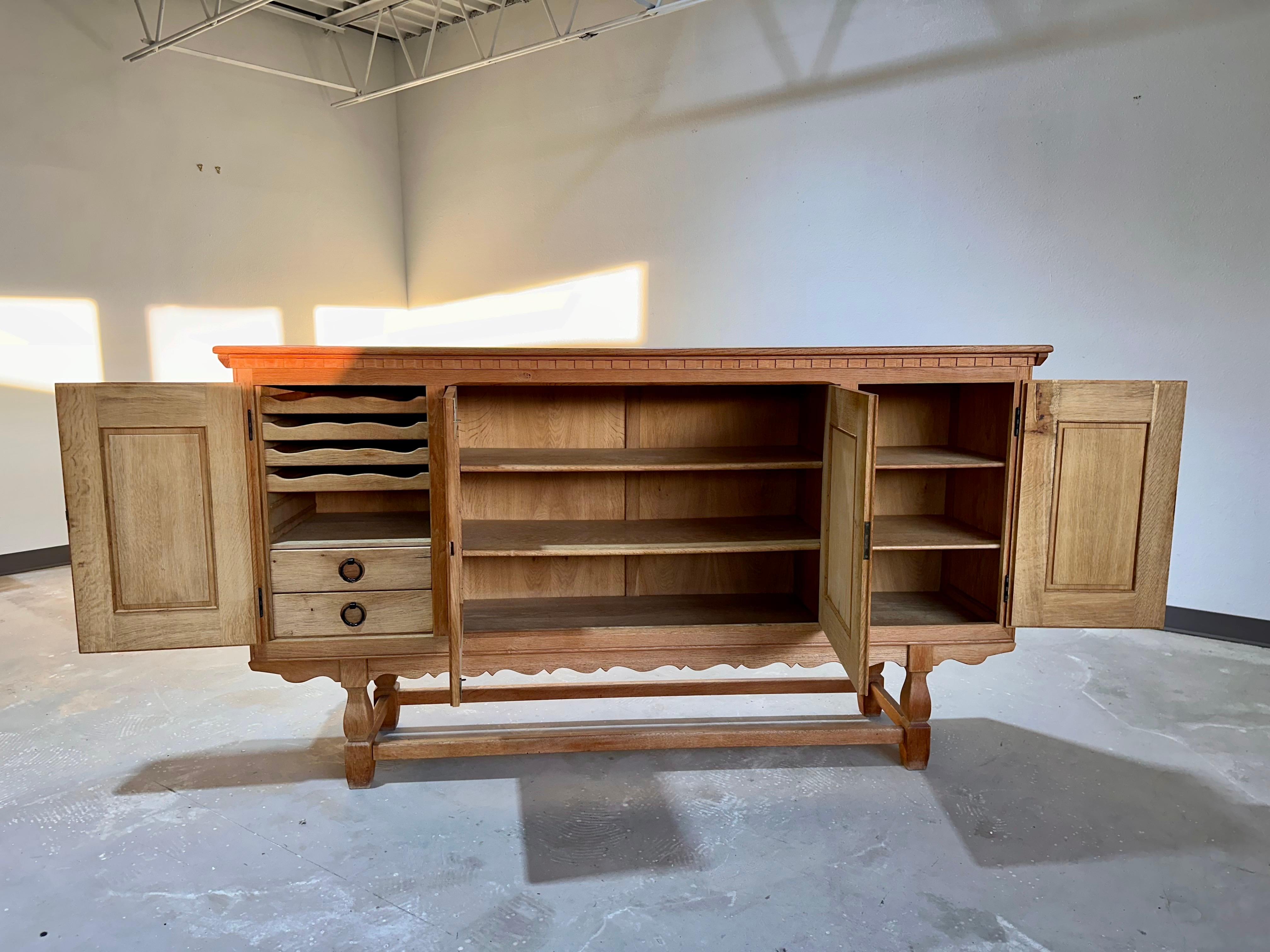Danish solid white oak brutalist highboard c.1960’s’s attributed to Henning Kjaernulf. Four locking door credenza/highboard with ironwork carving on outer doors and linen fold carving on center doors, and scalloped edging along bottom. This was