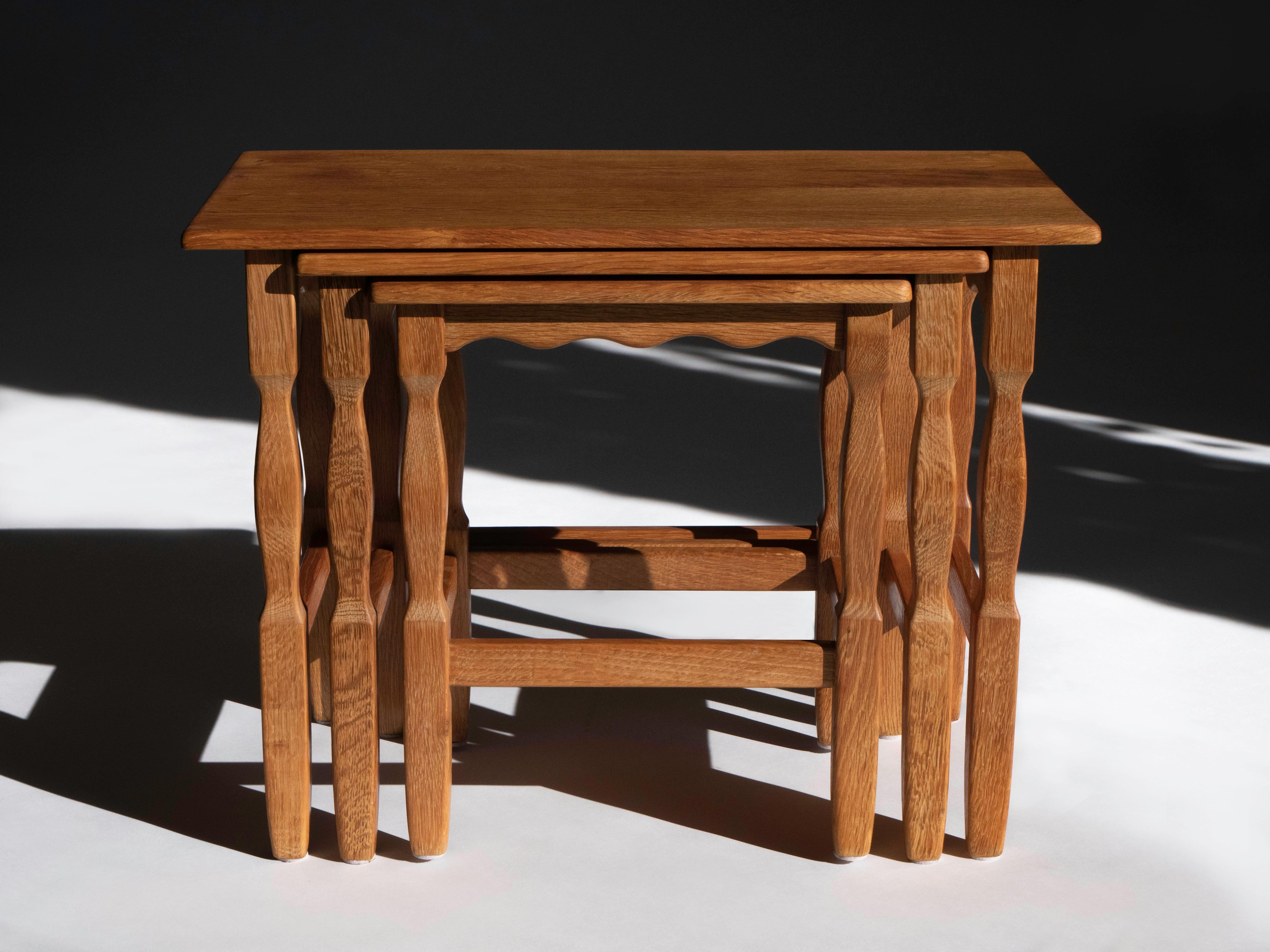 A remarkable set of 3 nesting tables in solid red oak by designer Henning Kjaernulf. Made in Denmark in the 1960's. 

A trio of highly detailed tables with carved legs, rounded edges, and scalloped trim bordering each table's top. They are in