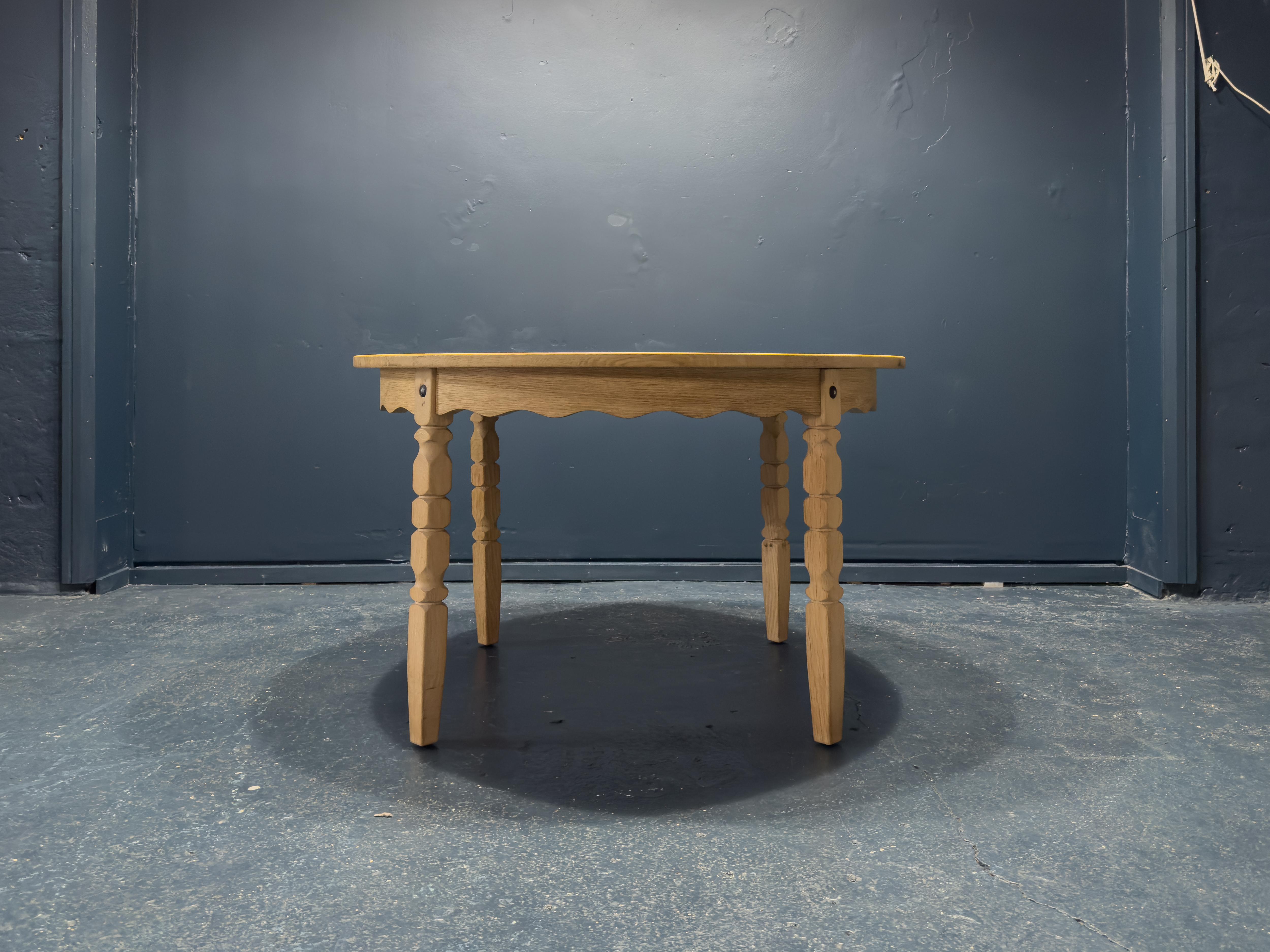 Conçue par le designer danois Henning Kjaernulf dans les années 1960, cette magnifique table en chêne massif est une véritable pièce d'apparat avec ses solides pieds sculptés et ses élégants détails festonnés. Le grain magnifique et la quincaillerie