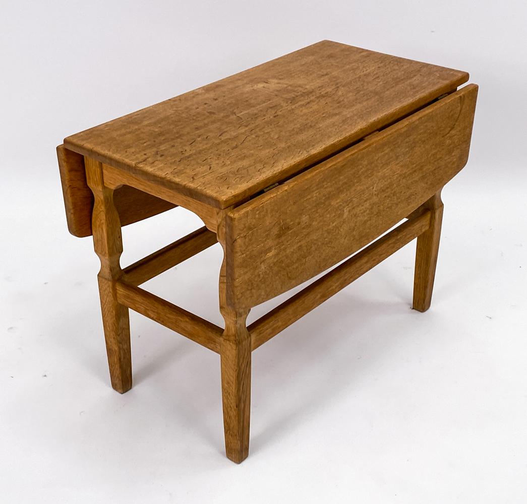 A charming Danish mid-century side table in study carved oak wood, designed by Henning Kjaernulf for EG Kvalitetsmobel. This drop leaf end table would blend seamlessly into a Scandinavian farmhouse inspired interior with subtle lines and blonde oak