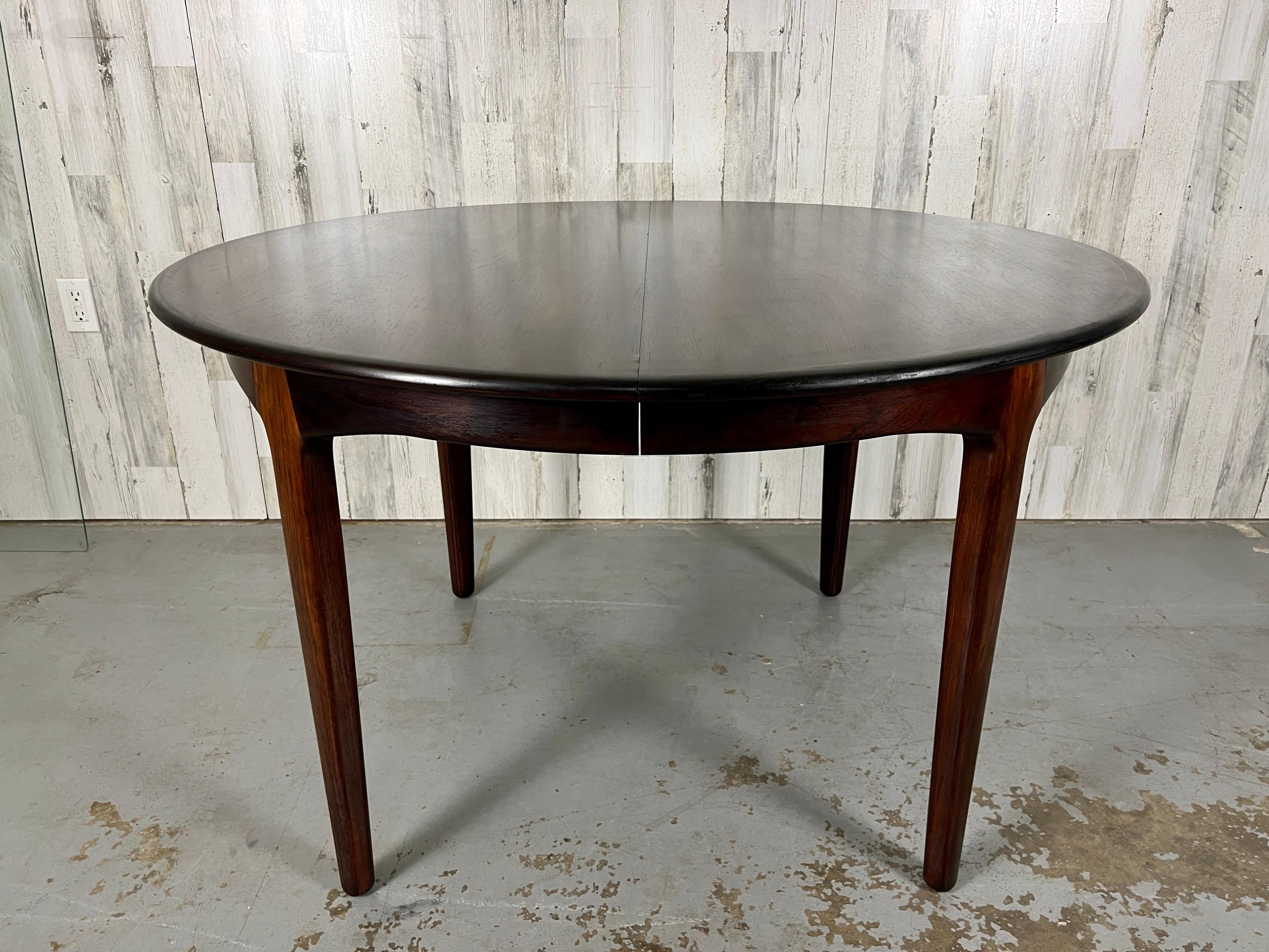 Combination of solid and veneered rosewood round Danish Modern dining table with four leaves, one has a matching apron the other three do not have the apron. This table can seat 10-12 people. Total width with leaves is 126