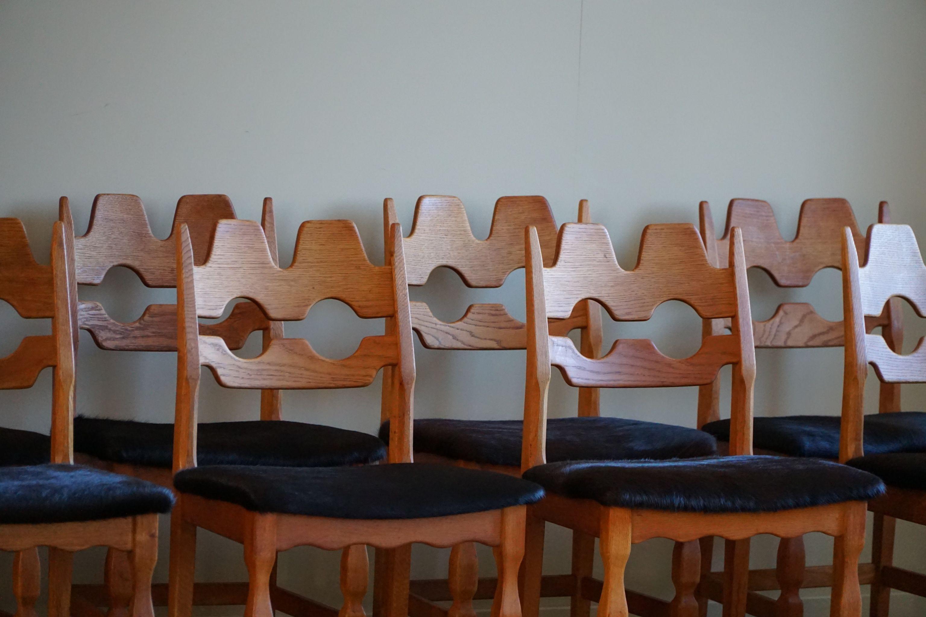 Un ensemble sculptural intrigant et populaire de 8 chaises de salle à manger classiques en chêne, dont les sièges sont recouverts d'une peau de vache noire de qualité. Conçu par Henning (Henry) Kjærnulf pour Nyrup Møbelfabrik - vers les années 1960.