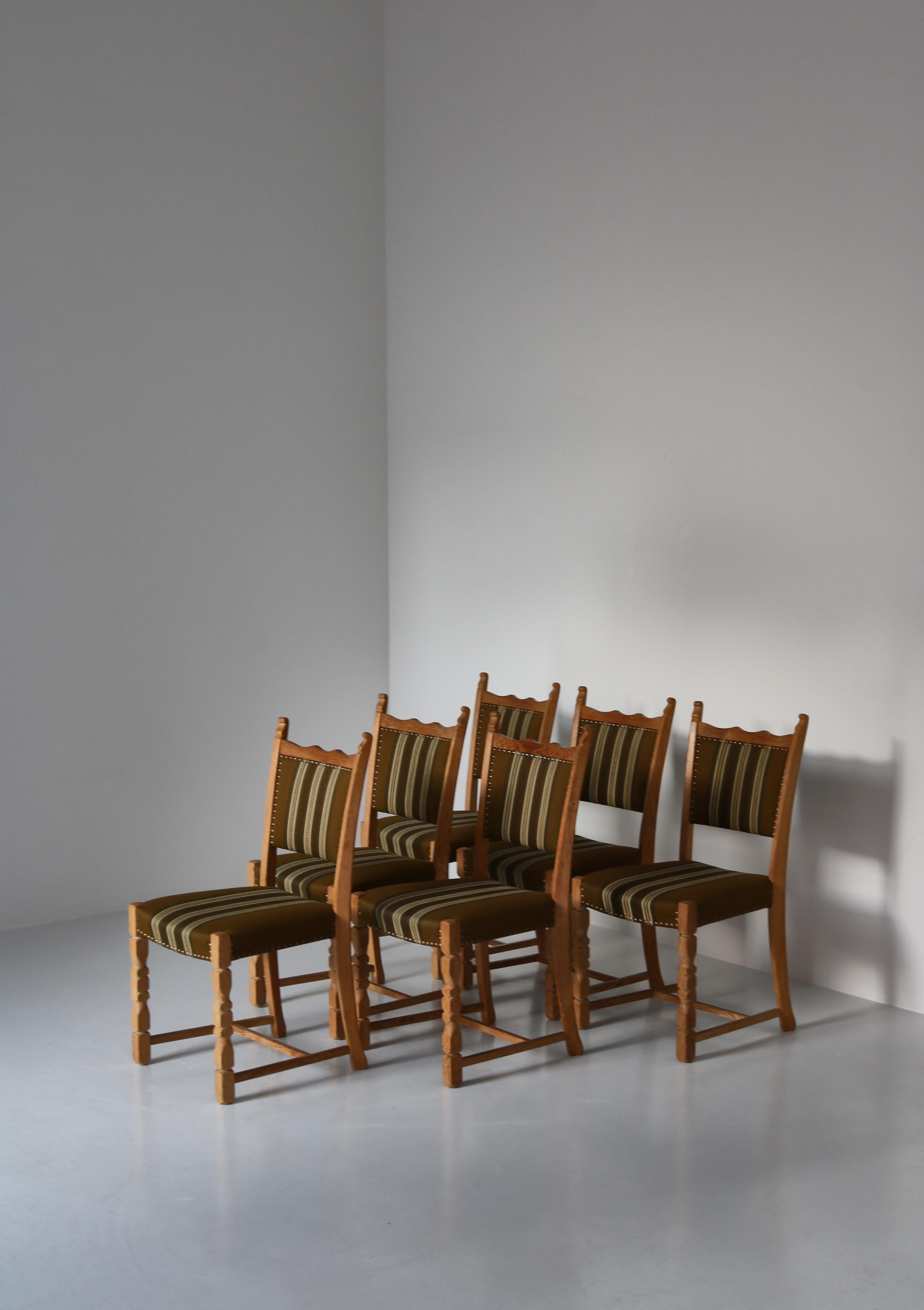 Vintage dining chairs in solid patinated Scandinavian oak tree and original wool upholstery. This model was designed in the 1960s and is ascribed to Henry Kjærnulff, Denmark. The style is modern but with playful hints to historical chairs. The frame