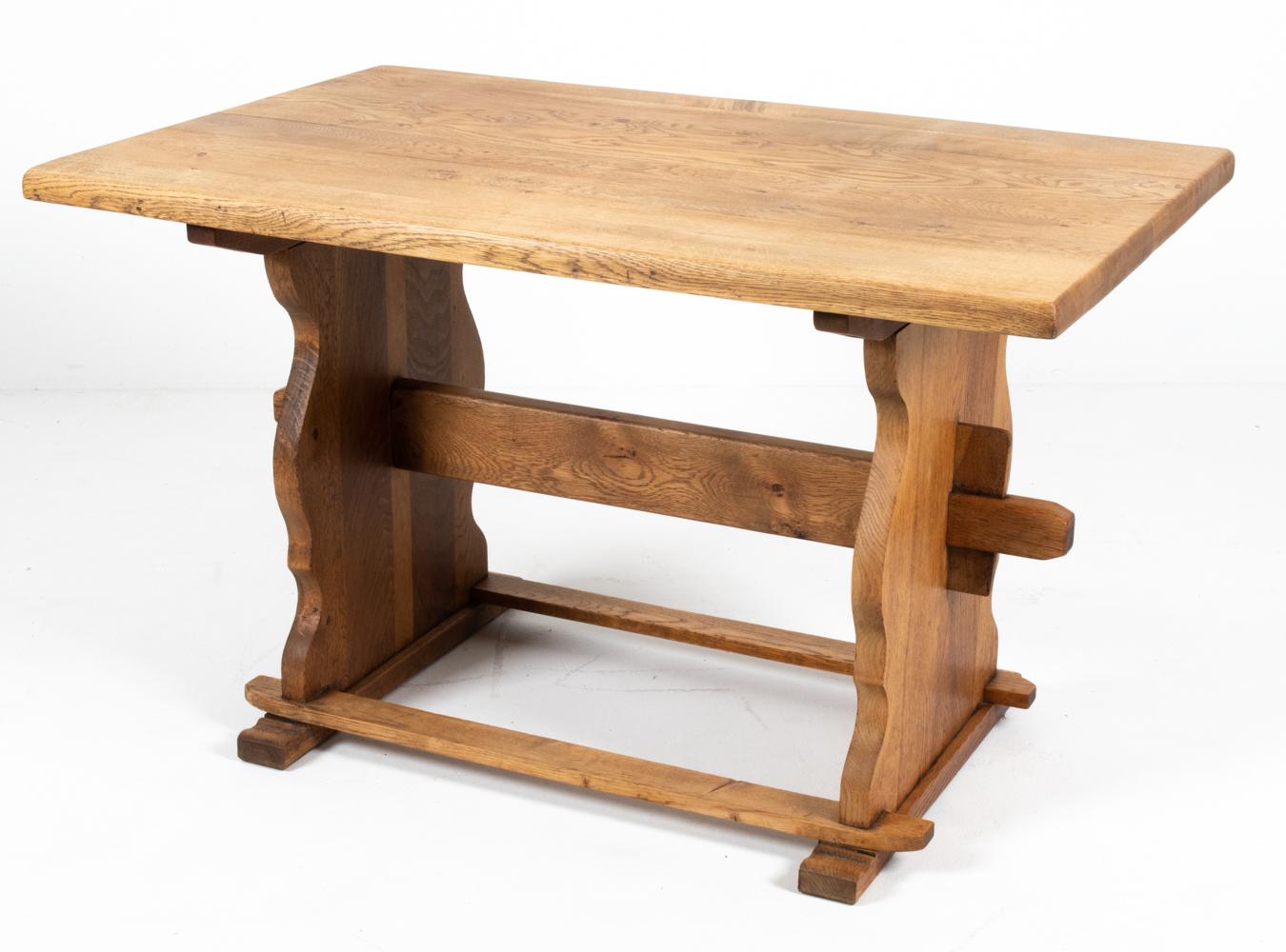This charming Danish mid-20th century dining table in carved oak wood is a fabulous example of Scandinavian provincial design. Full of farmhouse flair, this trestle base table features a sturdy design with a sculpturally carved base and thick