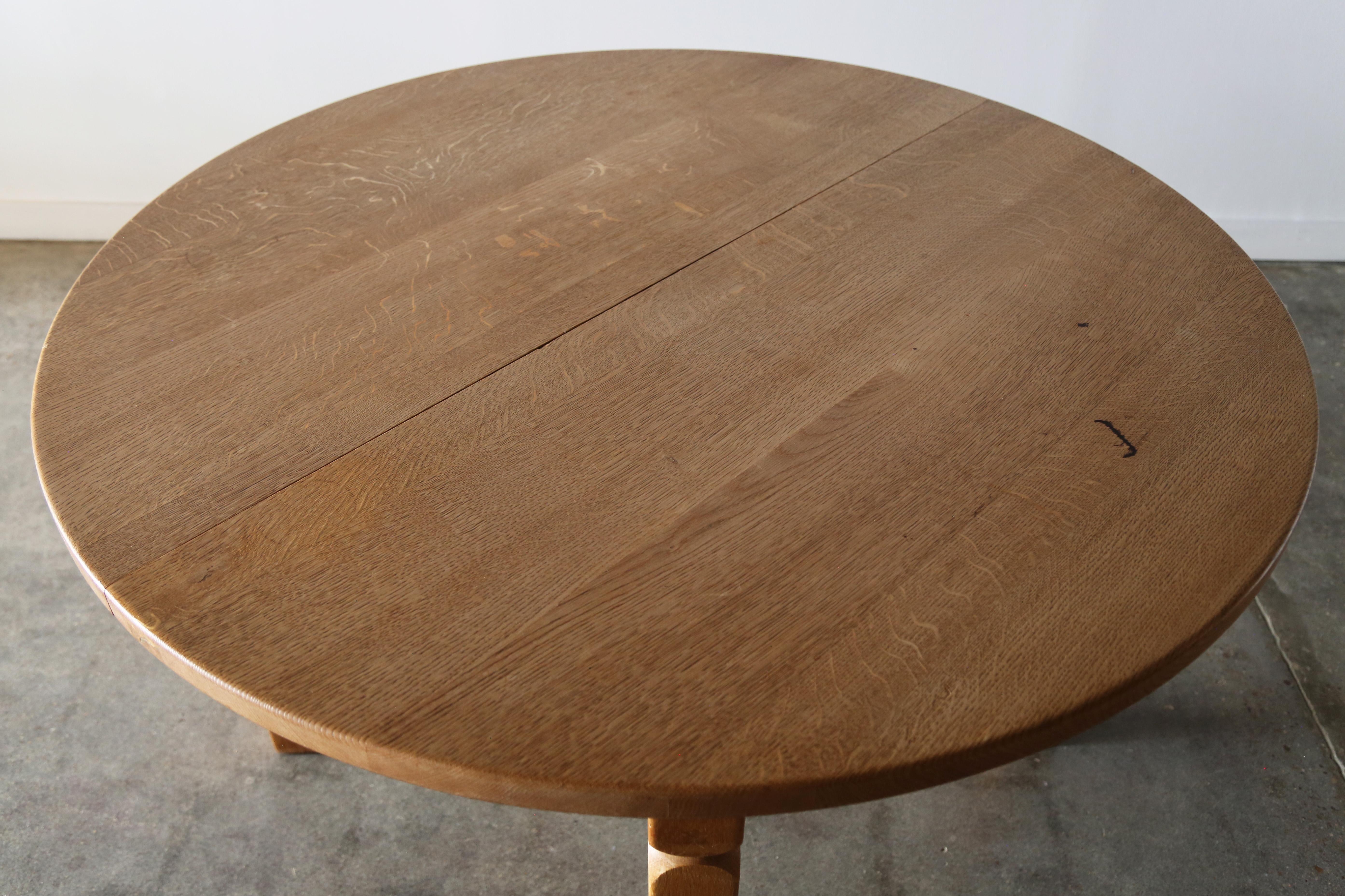 A brutalist white oak 1970’s dining table Designed by Henning Kjaernulf, well-renowned for his iconic farmhouse-inspired carved oak furniture designs, c. 1970s. Three leaves allow this circular dining table to extend from 47.25” diameter to a max