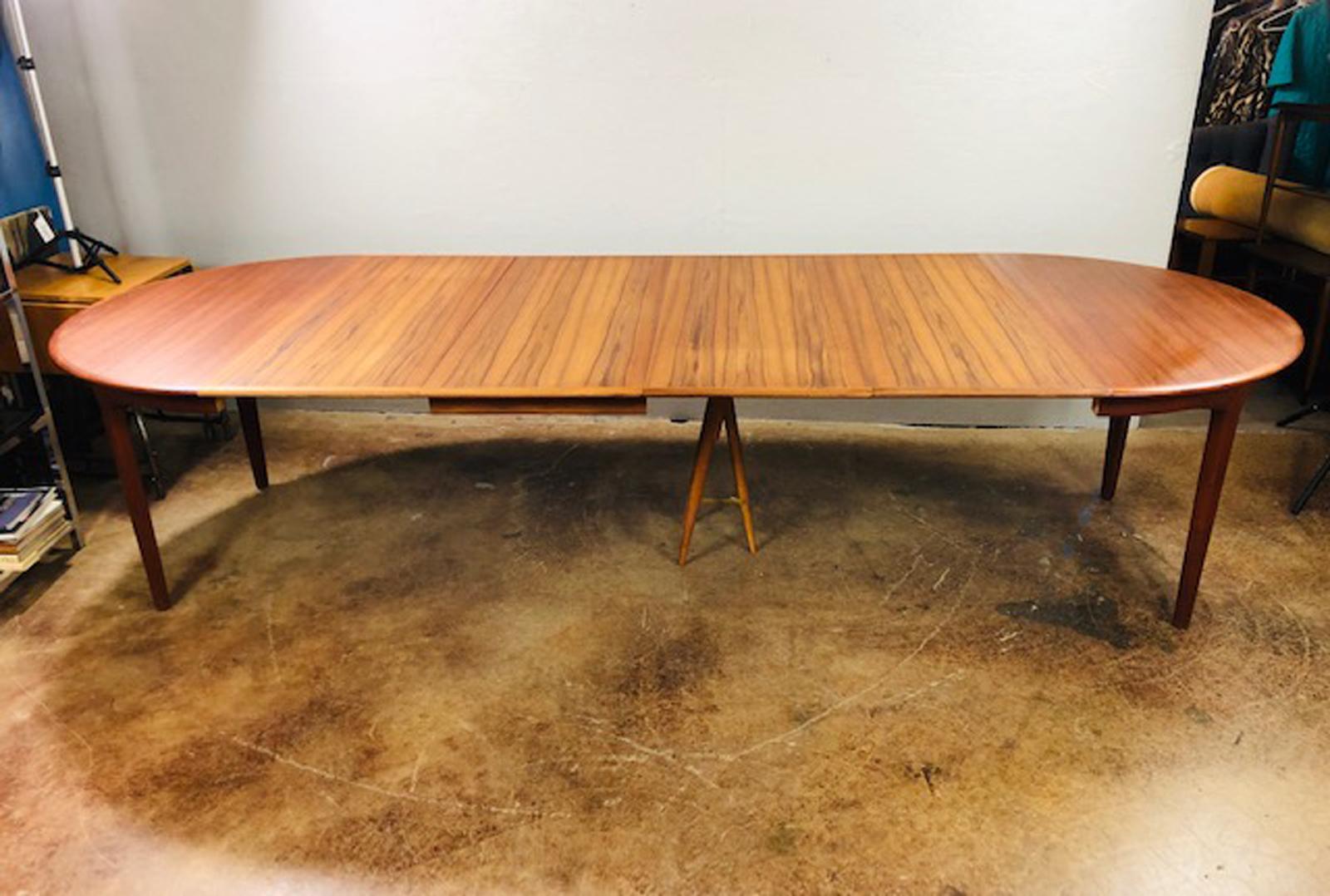 Henning Kjaernulf teak extension dining table handcrafted by the Danish maker Sorø Stolefabrik. This table includes four 20 inches leaves and a drop down centre leg that extends down when table is fully expanded, circa 1950s. This extends to a full
