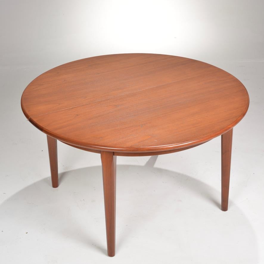 A Mid-Century Modern Danish round teak dining table by Henning Kjaernulf. Three leaves extend the table from 52