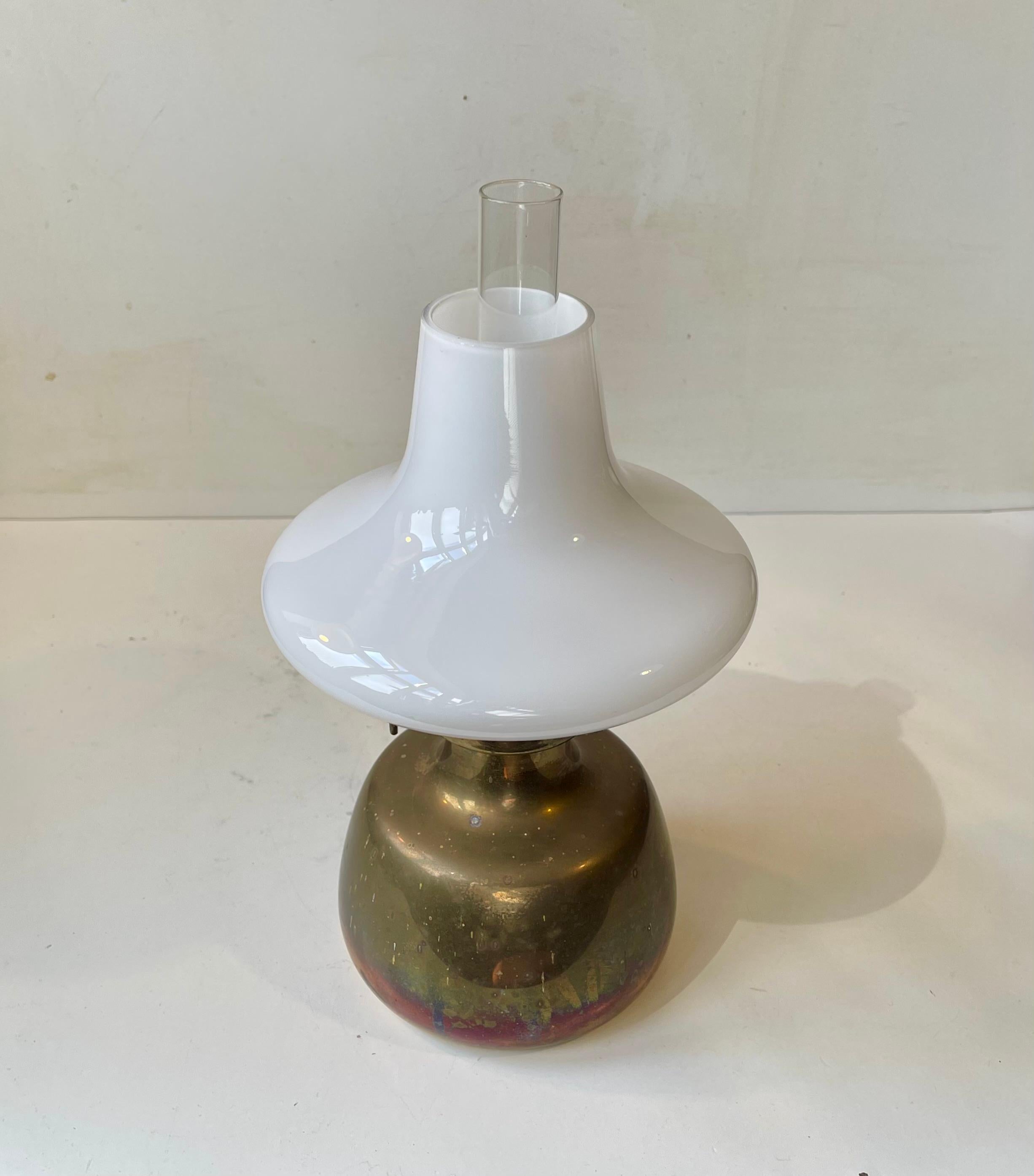 Conçue par Henning Koppel (1918-81) et fabriquée par Louis Poulsen au Danemark dans les années 1960, cette lampe à huile Petronella, fabriquée en laiton massif et en verre opalin, est devenue une icône du design. Il est mécaniquement sain et