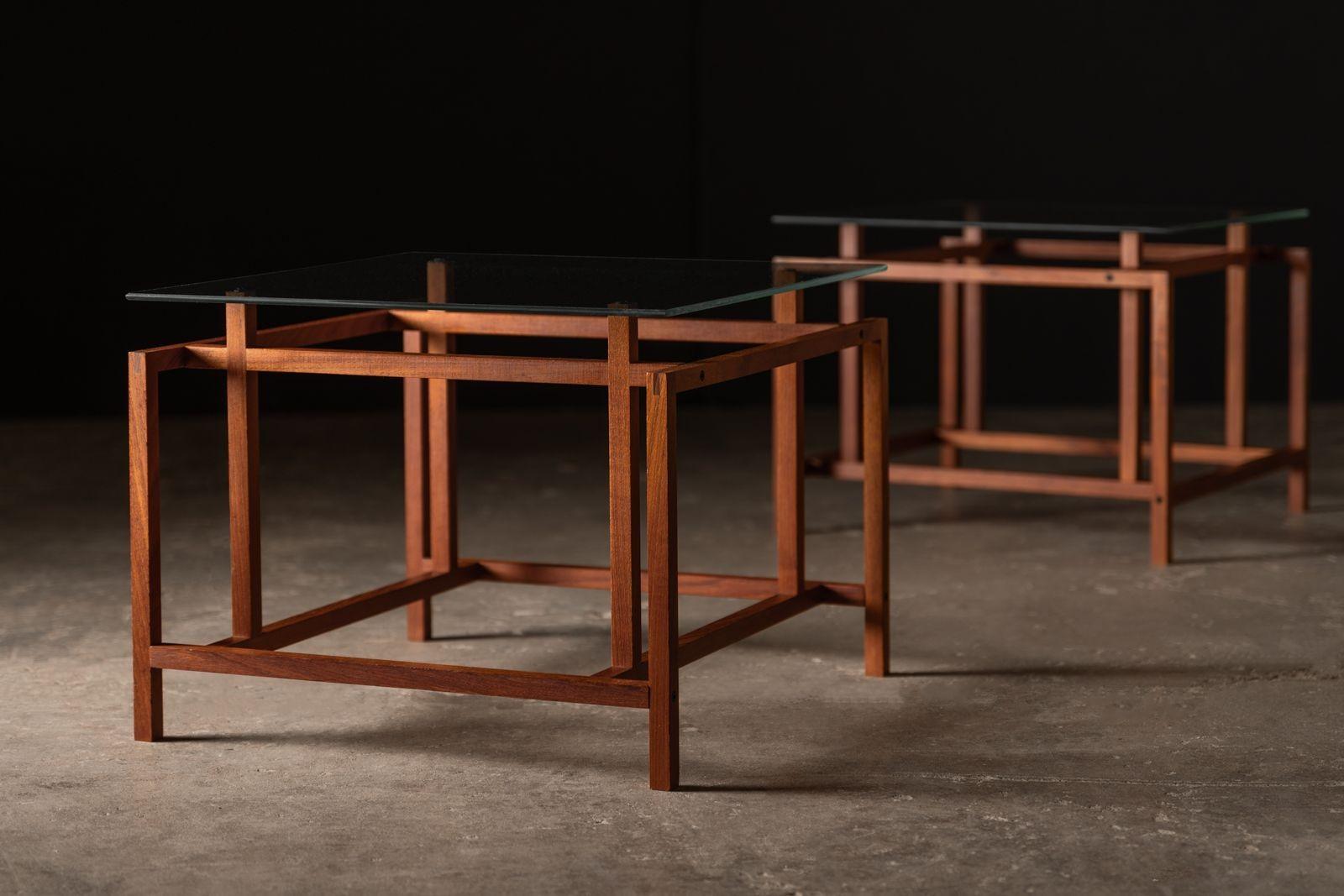 Coppia di tavolini architettonici in teak con piani in vetro originali di Henning Nørgaard per Komfort. La base geometrica minimalista in teak massiccio mostra un'eccellente maestria, con giunzioni a mortasa e tenone e a pettine. Conserva