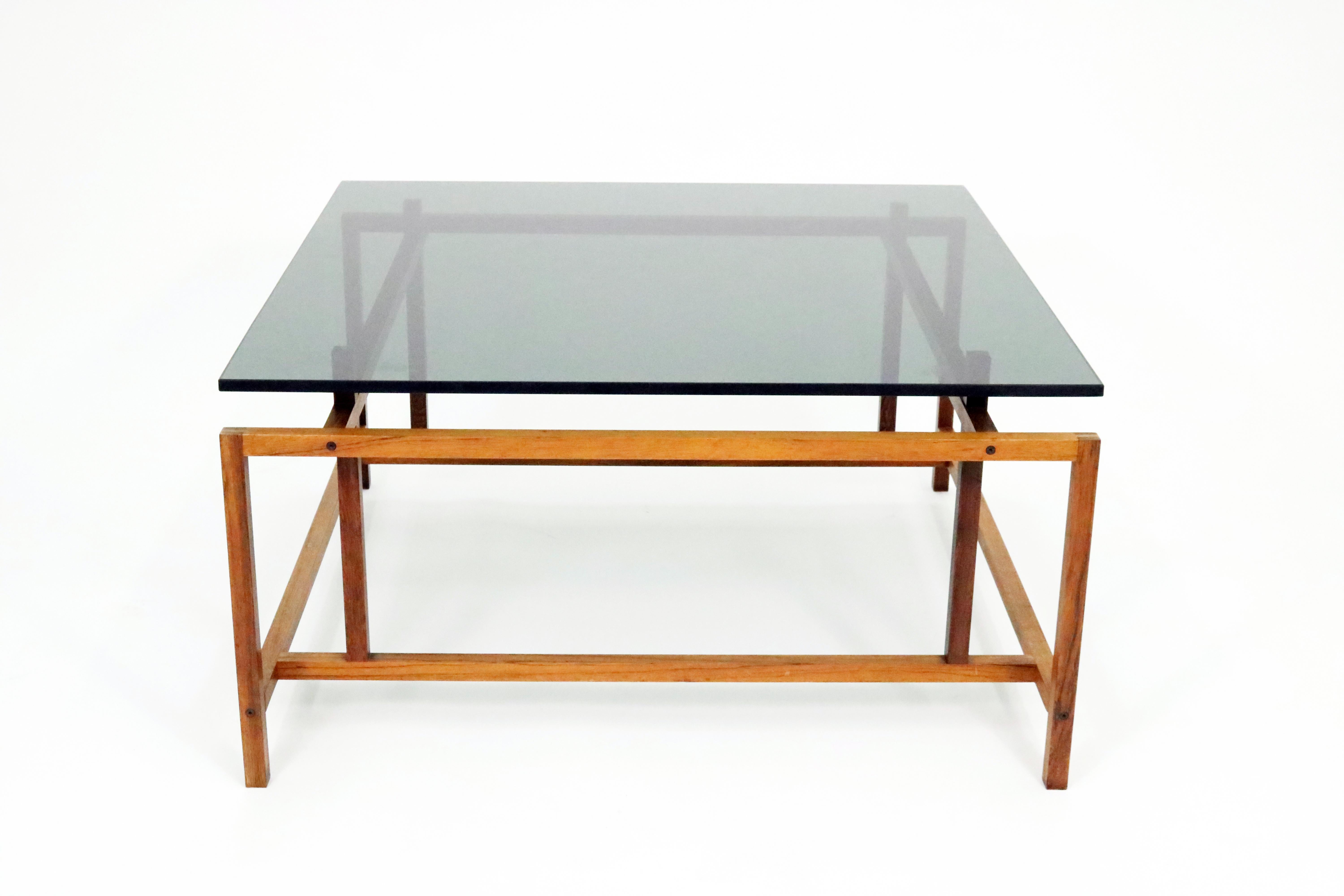 A sleekly architectural Scandinavian Modern Danish coffee table in rosewood and smoked glass by Henning Norgaard for Komfort. 

Minimalist geometric solid rosewood base displays excellent craftsmanship, with both mortise-and-tenon and finger