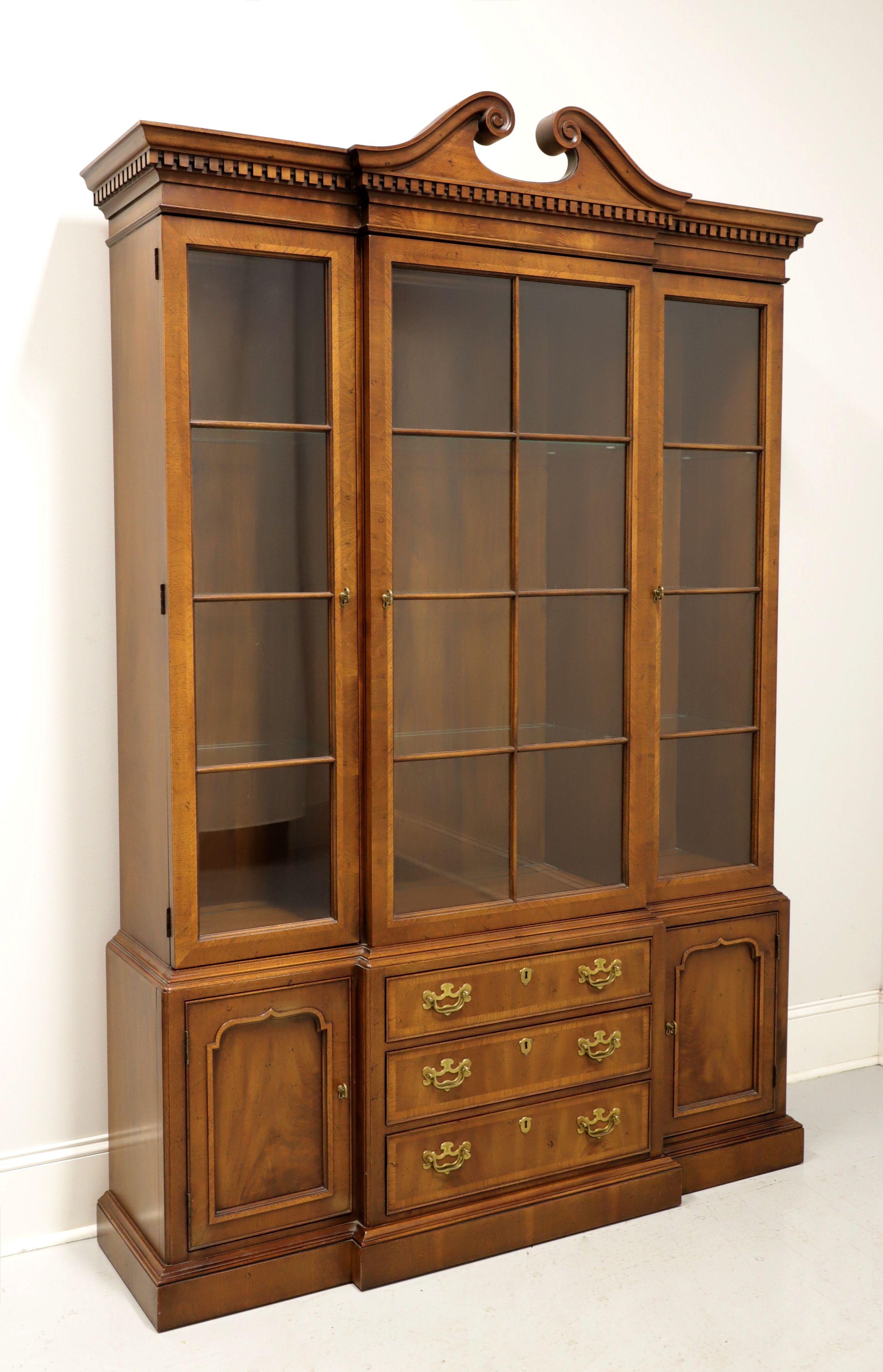 A Traditional style breakfront china cabinet by Henredon, from their 18th Century Portfolio. Walnut with banded drawer fronts and brass hardware. Top cabinet has three separate areas, each area has a paned glass door, three adjustable plate grooved