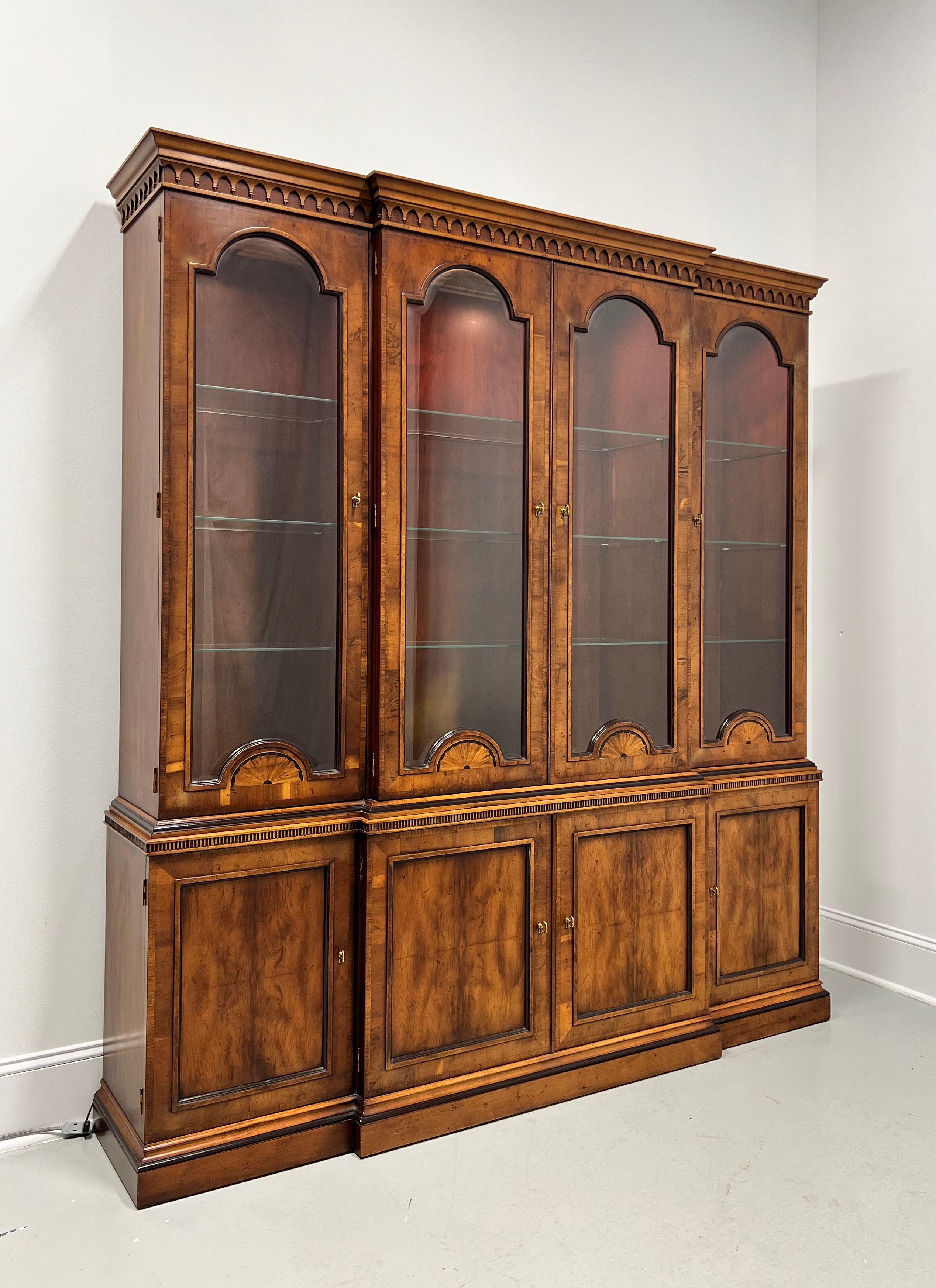 A Georgian style breakfront bookcase china cabinet by Henredon, from their 18th Century Portfolio. Yew wood with inlaid details, brass hardware, crown & stylized dentil moulding to top, arched solid glass doors with arched shell marquetry, ogee edge