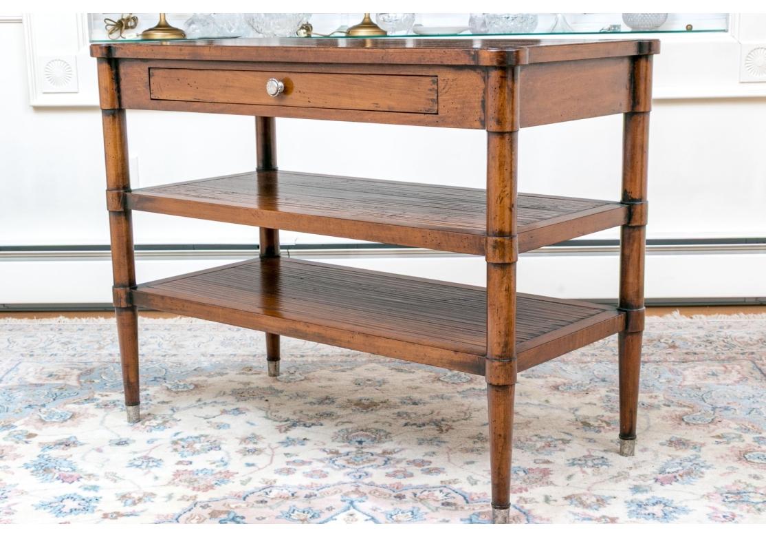 A side table by Henredon from their Acquisitions collection with planked hand hewn-style finish, cookie corners, shallow drawer, with silver-tone knob and resting on round tapering legs with brass caps. Original hangtag included.

Dimensions: 37