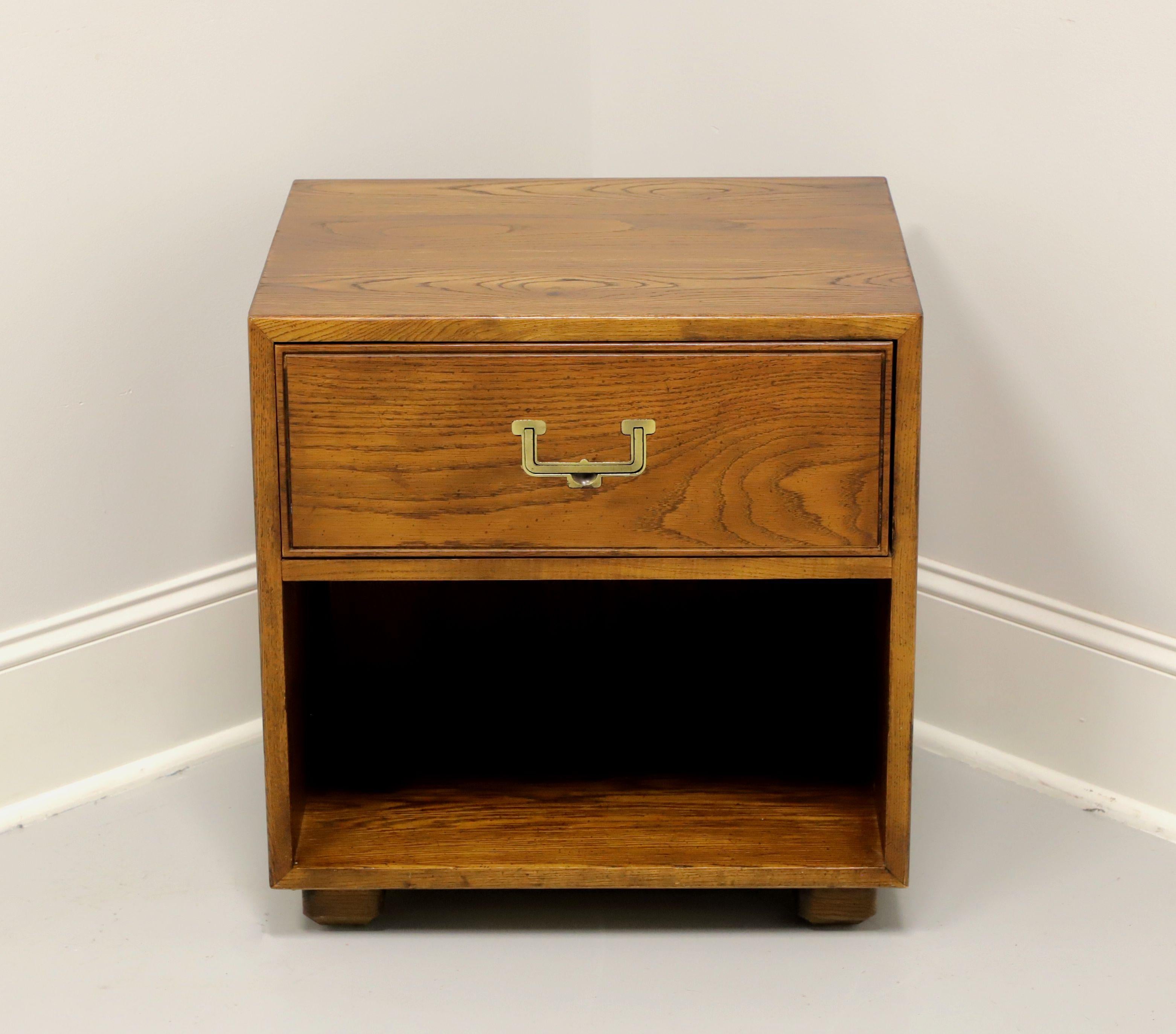 A Campaign style nightstand by Henredon, from their Artefacts Collection. Pecan, or similar nutwood, with brass hardware and block feet. Features one dovetail drawer above an open cabinet. Has a pre-drilled hole in the back for electrics. Made in
