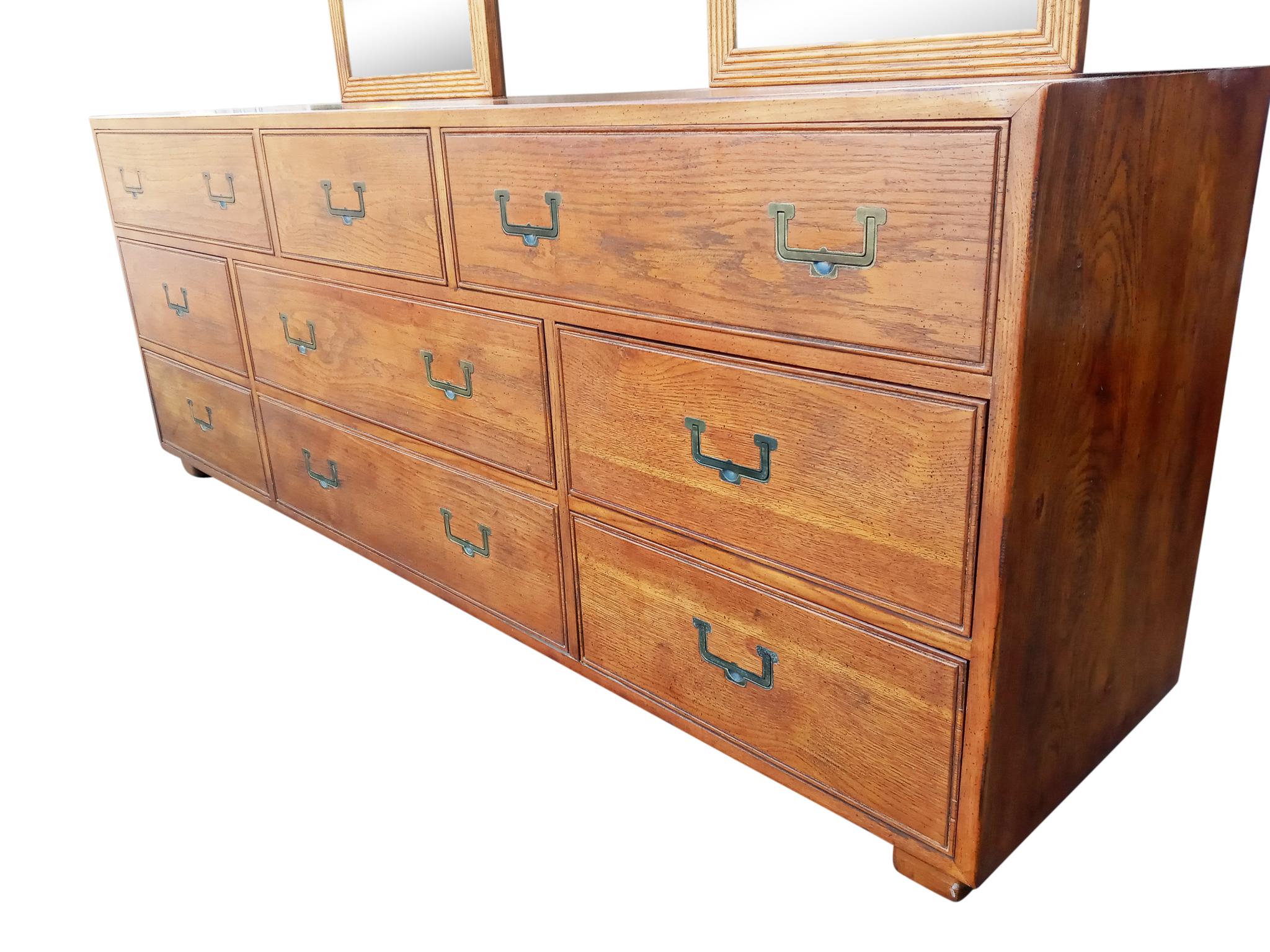 Heirloom-quality Mid-Century Modern long dresser with mirrors by Henredon, part of the Artefacts collection. Features nine drawers and a pair of matched and subtly detailed attached mirrors. Finely crafted aged oak construction with laquered brass