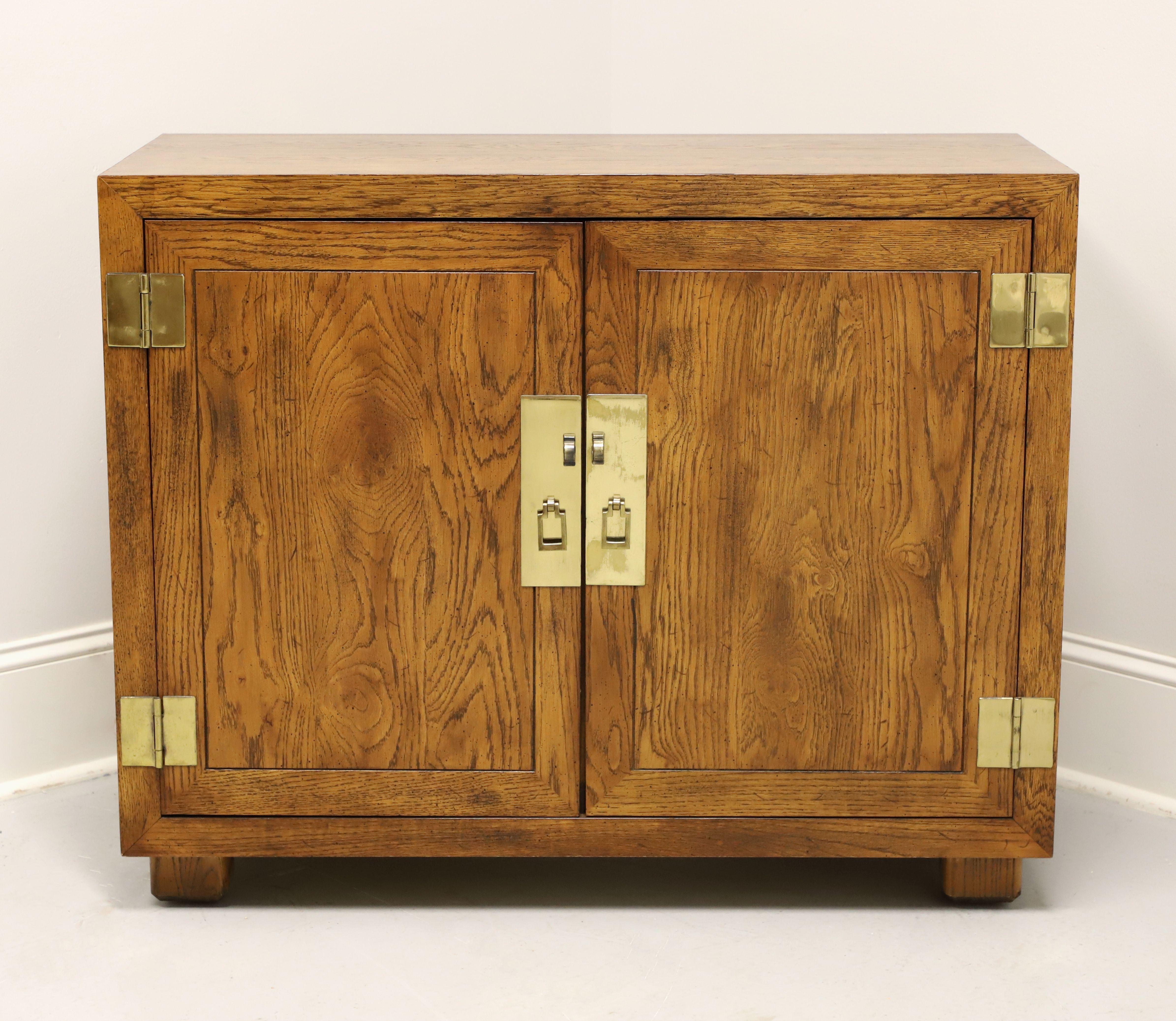 A Campaign style console cabinet by Henredon, from their Artefacts Collection. Knotty oak with slightly distressed finish, banded door fronts, smooth surface top, brass hardware, and block feet. Features a two door cabinet revealing one drawer of