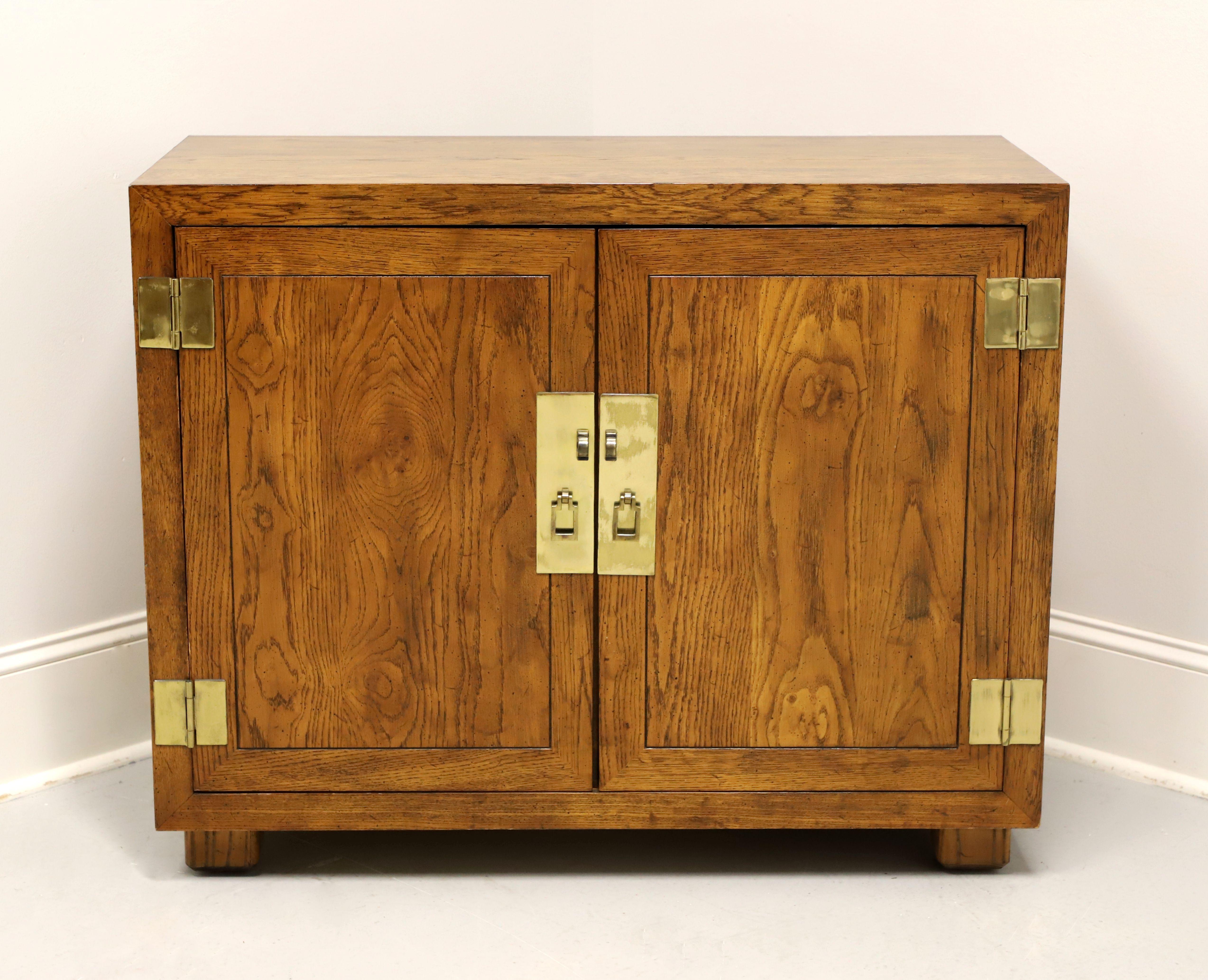A Campaign style console cabinet by Henredon, from their Artefacts Collection. Knotty oak with slightly distressed finish, banded door fronts, smooth surface top, brass hardware, and block feet. Features a two door cabinet revealing one drawer of