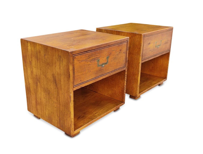 Heirloom-quality Mid-Century Modern nightstands or end tables by Henredon, part of the Artefacts collection. Finely crafted aged oak construction with lacquered brass recessed drawer pulls. Single drawers with open storage space below. Factory