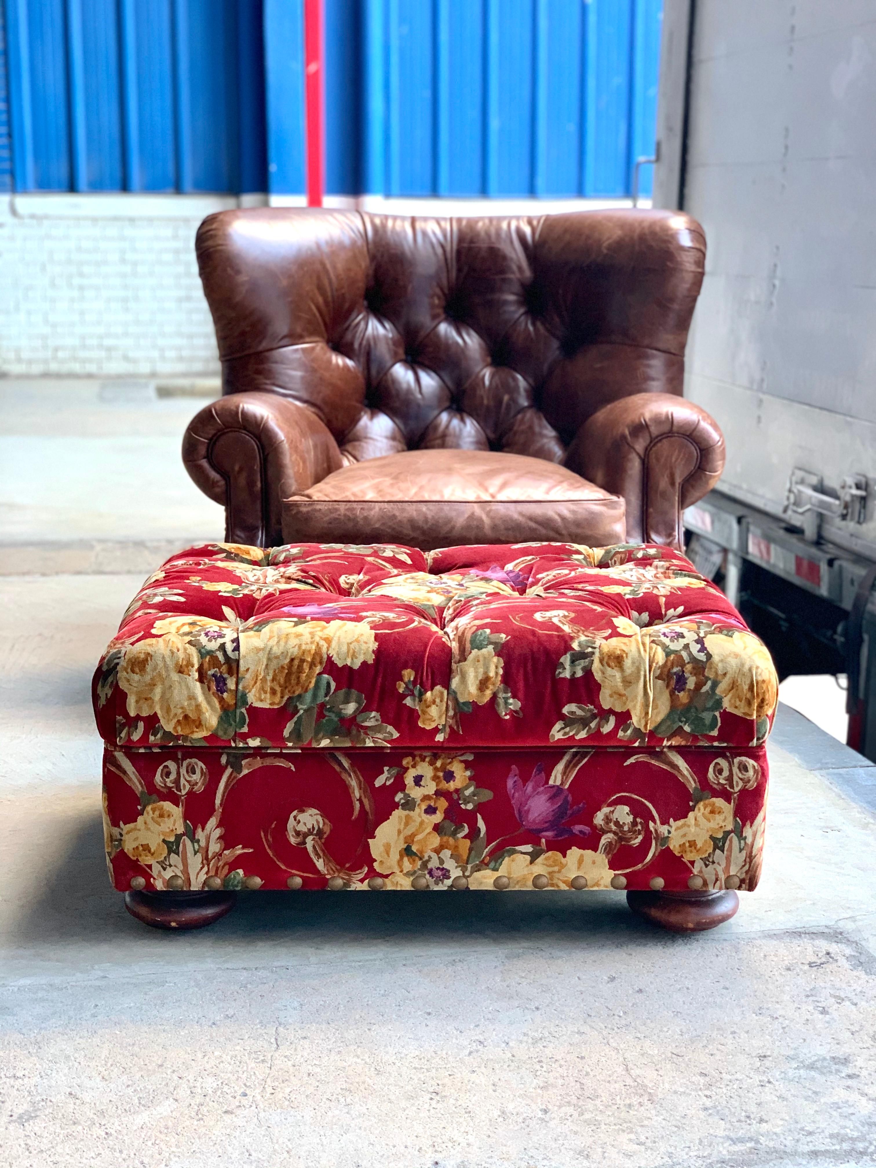 Iconic brown leather writer's lounge, armchair, red velvet floral ottoman. This iconic winged club chair with bold nailhead trim has a Classic tufted back and burnished mahogany bun feet. Ralph Lauren custom red velvet floral writer's ottoman