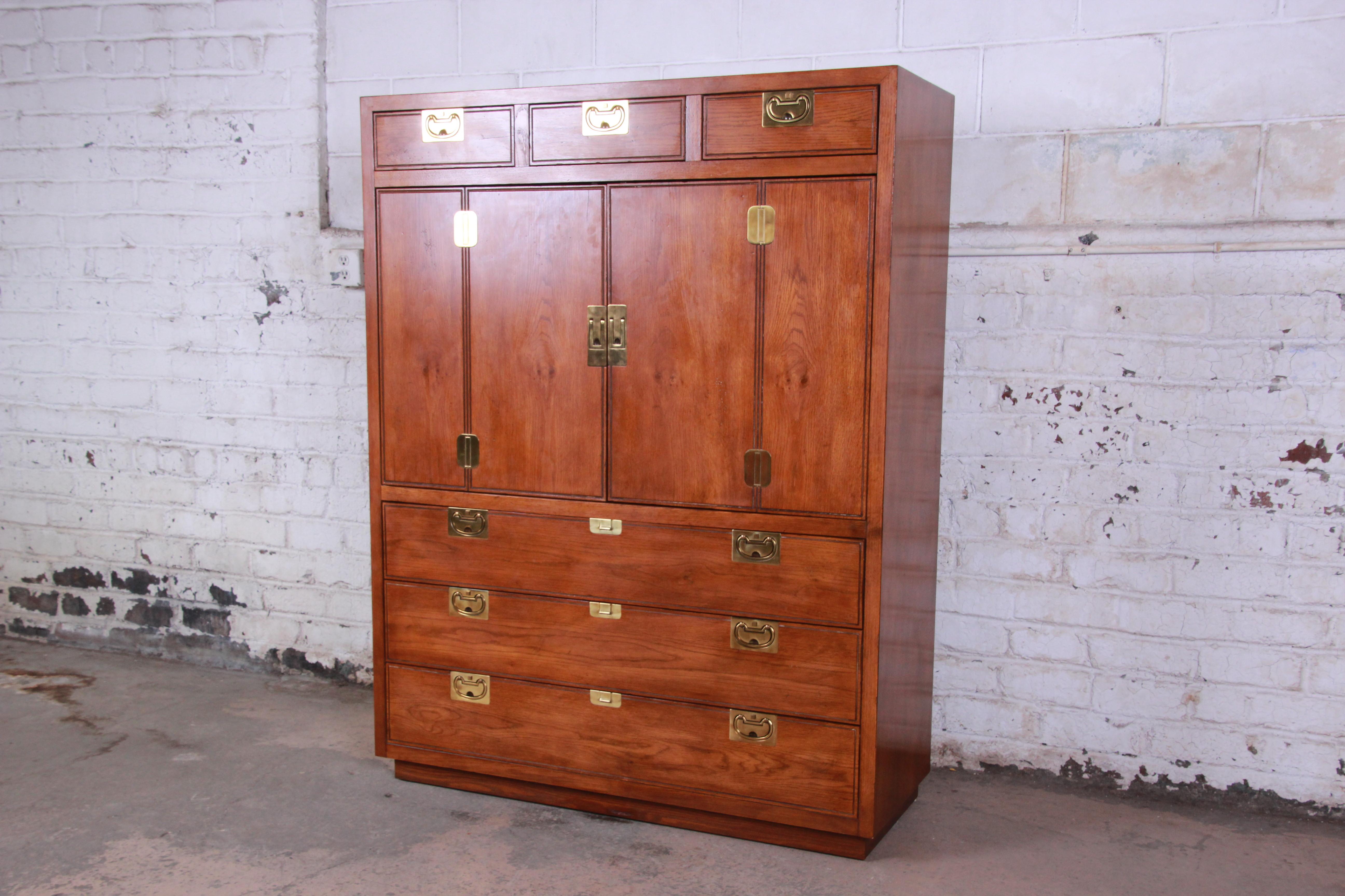 Offering a very nice and spacious Henredon Campaign style oak gentlemen's chest or armoire from the Bel Air line. The top of the chest offers three drawers for storage and just below are two large cabinet doors that open to a large storage and