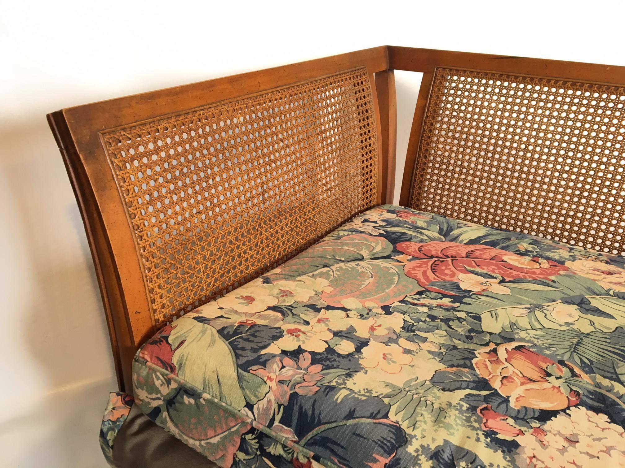 Vintage Henredon tuxedo sofa features cane back and sides and tapered legs. Upholstery was redone some years ago but still in good condition. Reupholstered with skirt, which is not original to the piece (skirt was lifted for photos). Caning is in