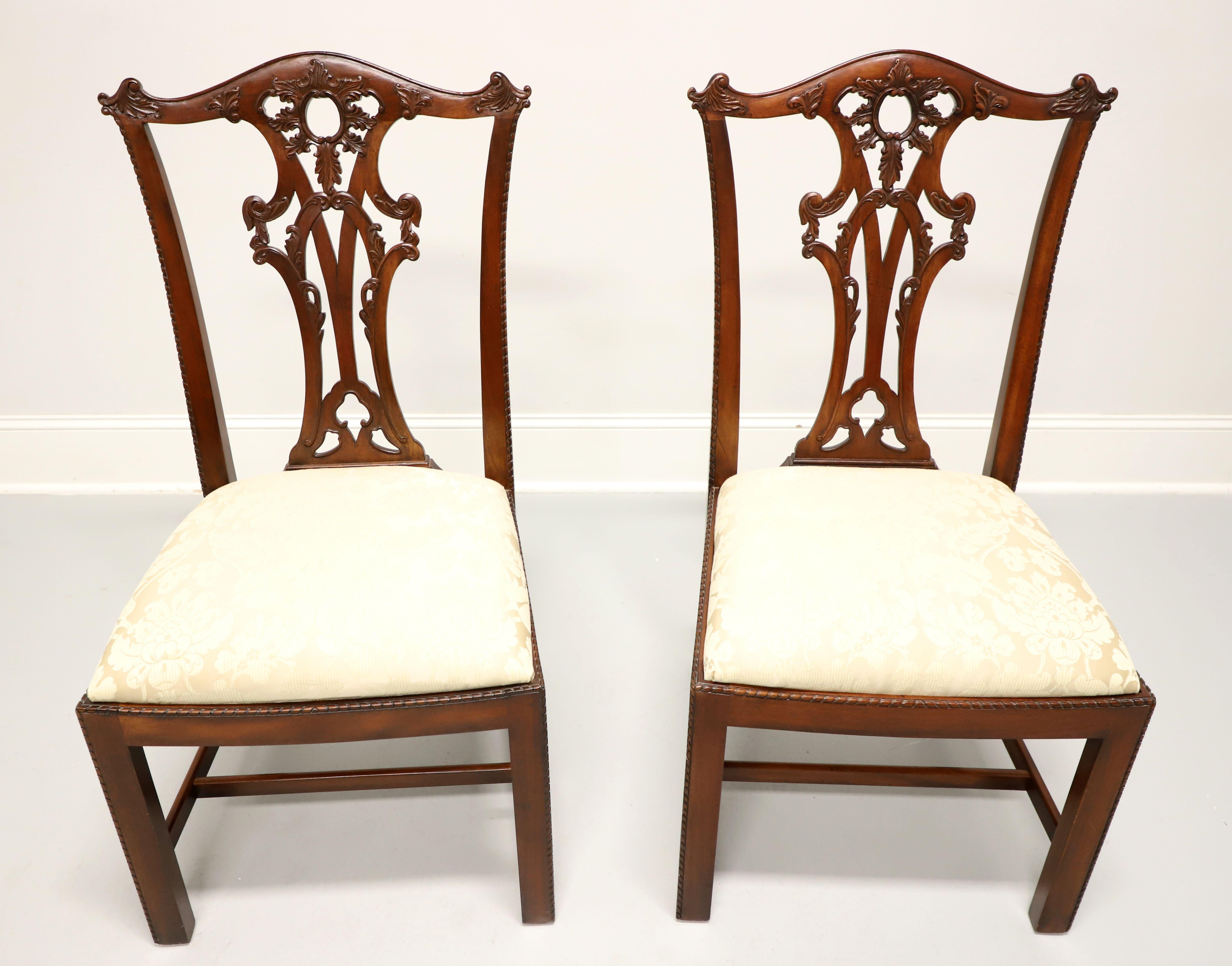 A pair of Chippendale style dining side chairs by Henredon. Solid mahogany with decoratively carved crest rail, back rest, carved beading to edge of stiles, seat edge & edges of the front straight legs with stretchers. Seat upholstered in a neutral