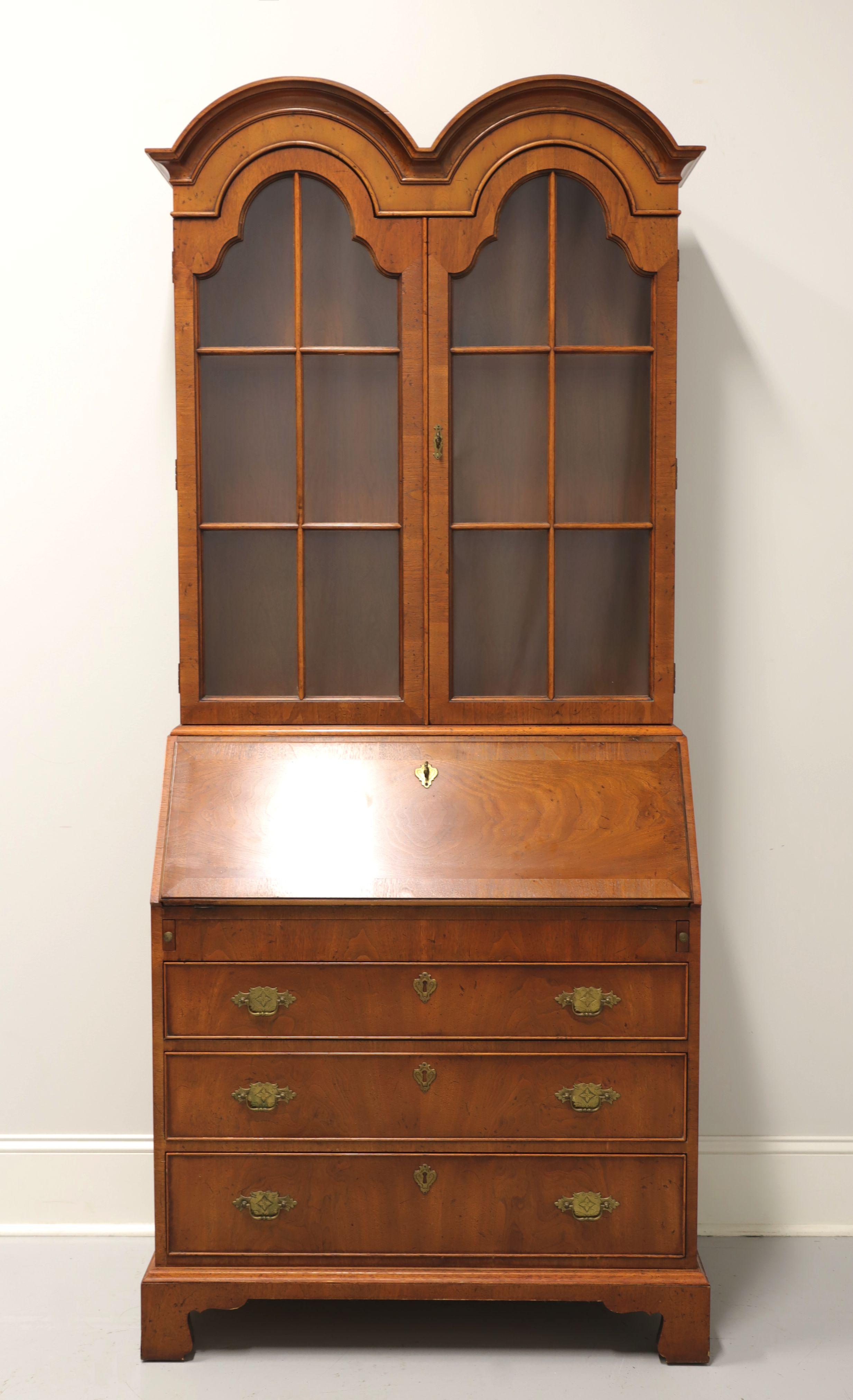 A Chippendale style secretary desk by Henredon, from their Folio 10 Collection. Burl walnut with brass hardware, double bonnet top, crown moulding, banded desk front and bracket feet. Upper cabinet features two arched doors with paned glass